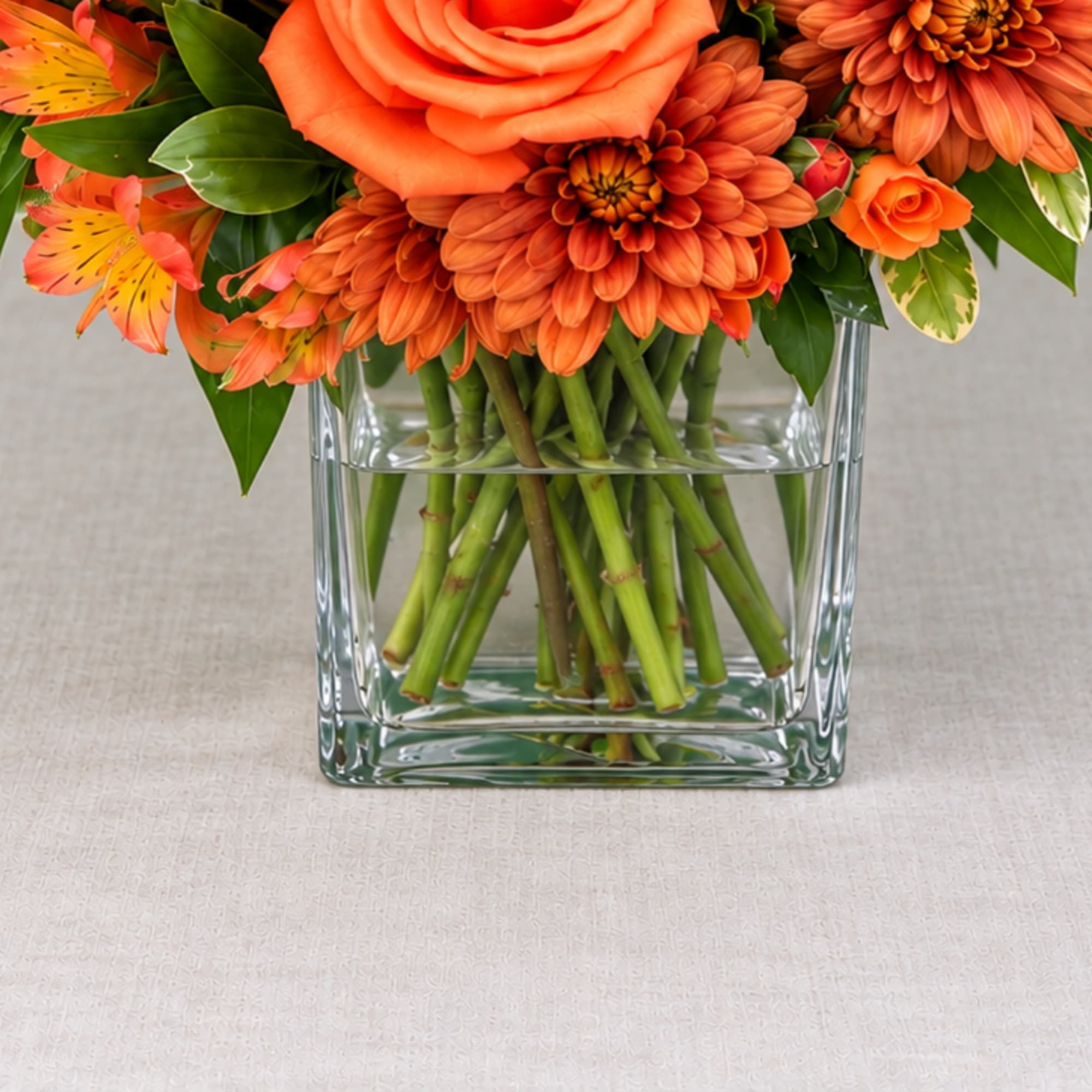 Orange floral arrangement in a clear square glass vase