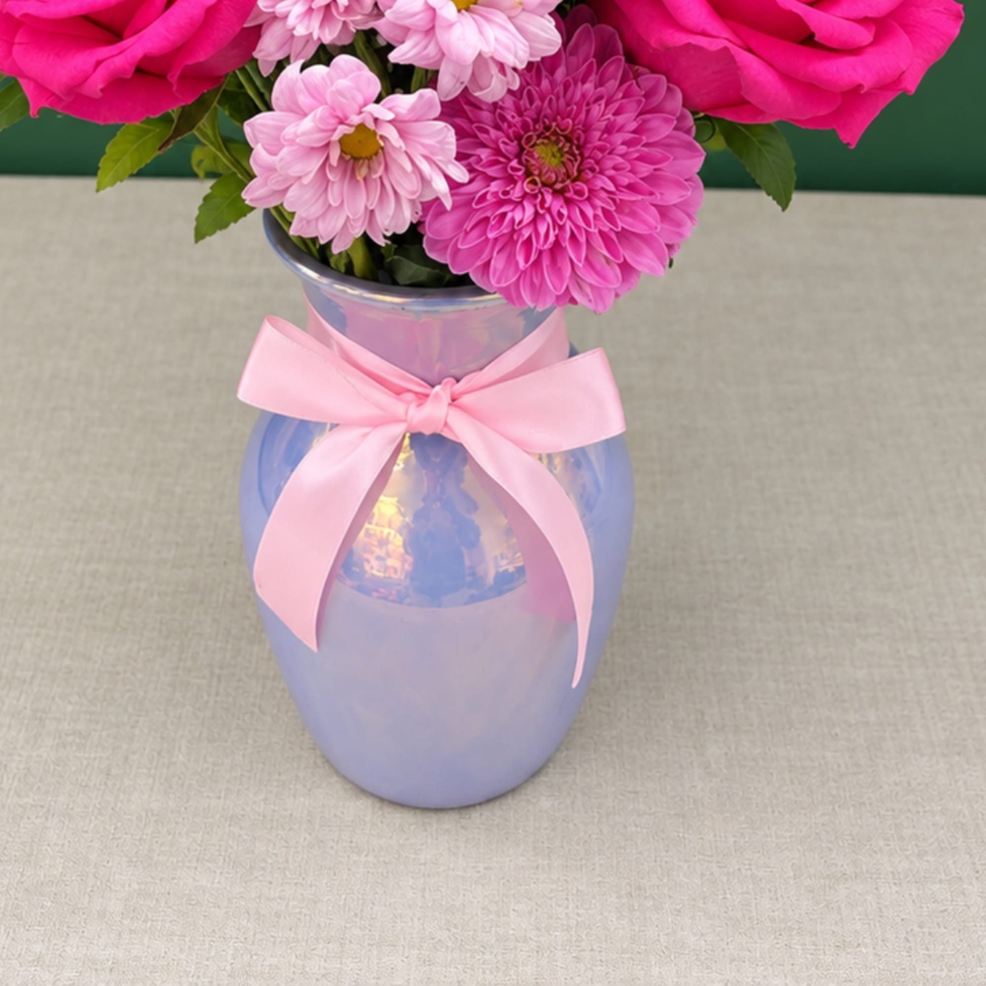 Pink flowers in a lavender vase with a pink ribbon