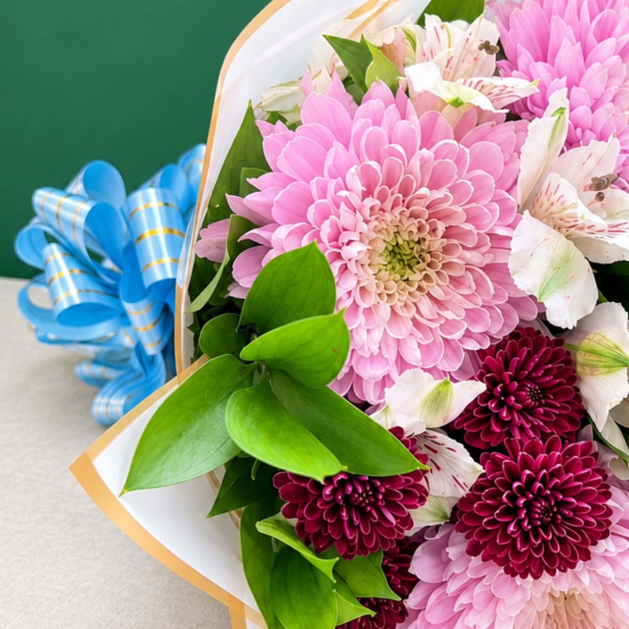 Bouquet of pink and burgundy chrysanthemums with white alstroemeria and a blue ribbon