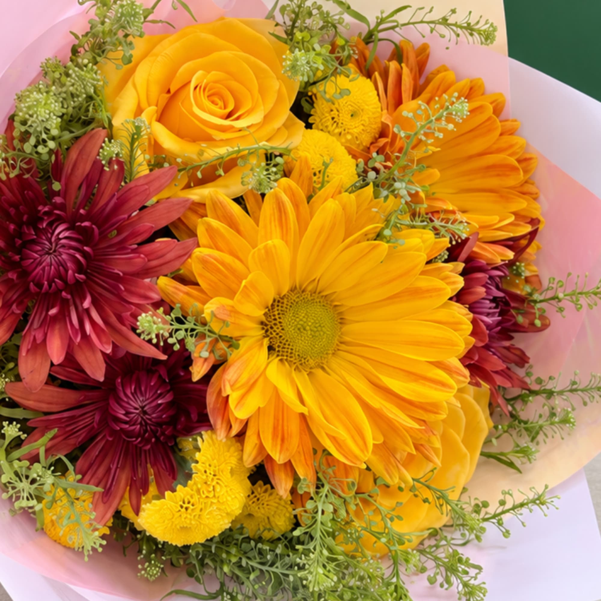 Bouquet of yellow and burgundy flowers wrapped in pink paper