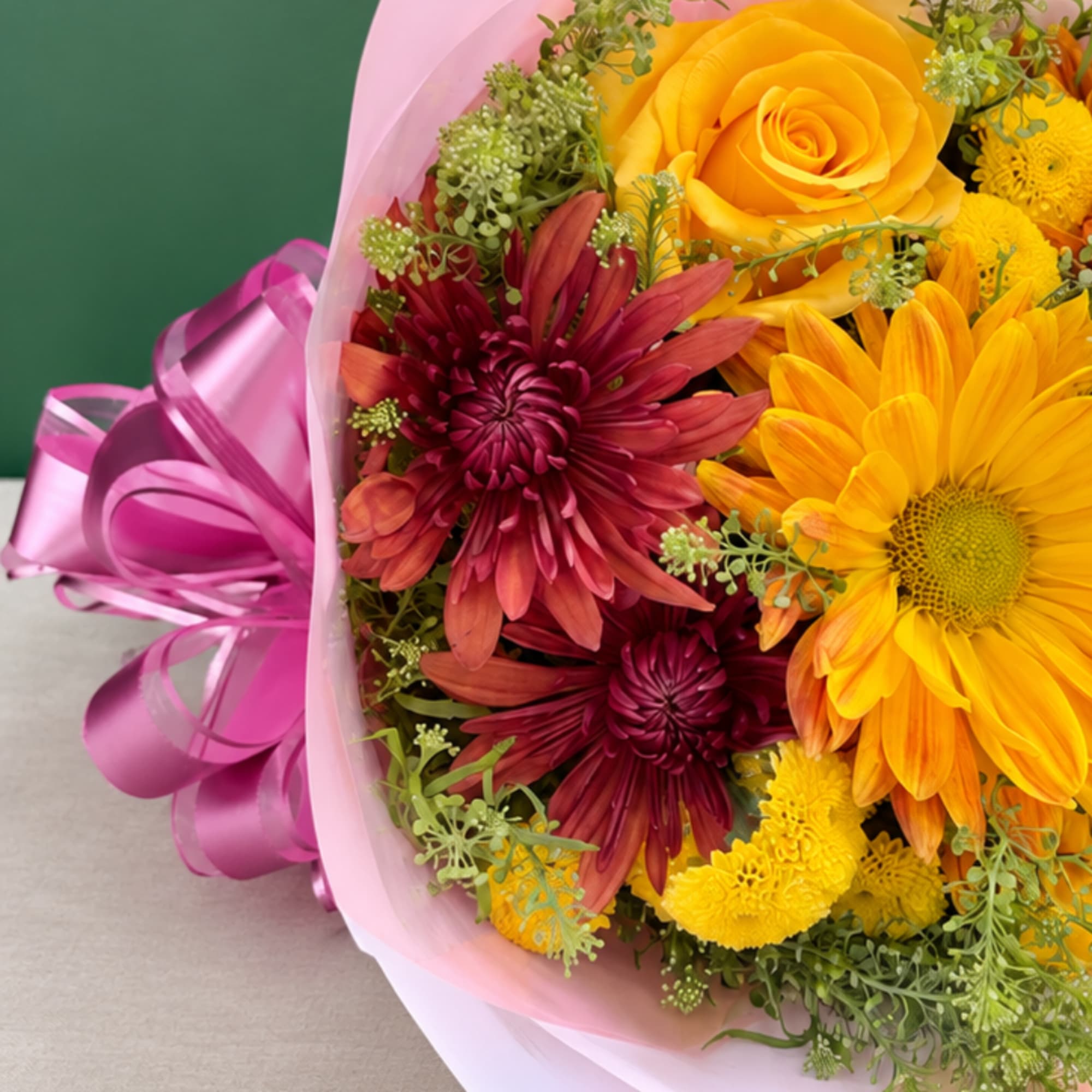 Bouquet of yellow and burgundy flowers wrapped in pink paper with a ribbon, photo 3 of 3