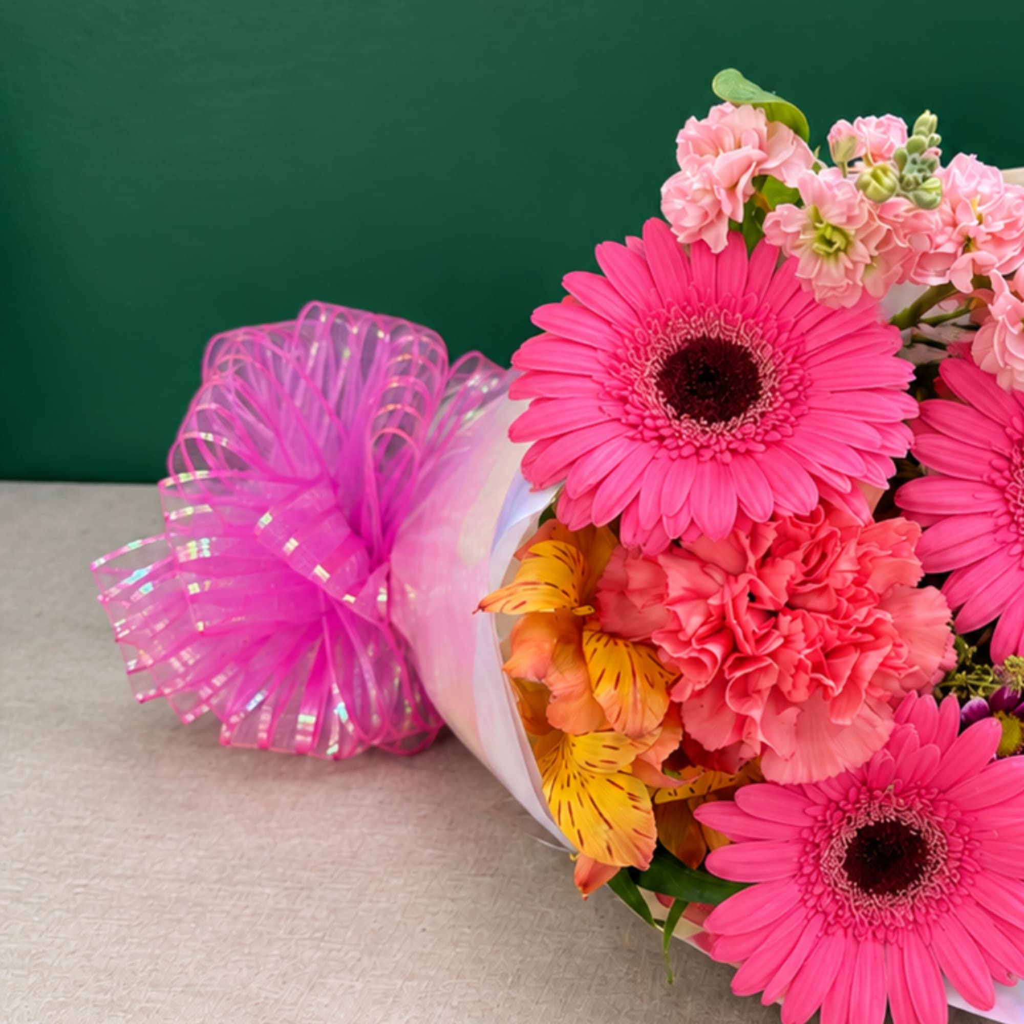 Bouquet of pink gerbera daisies and mixed blooms wrapped with pink ribbon