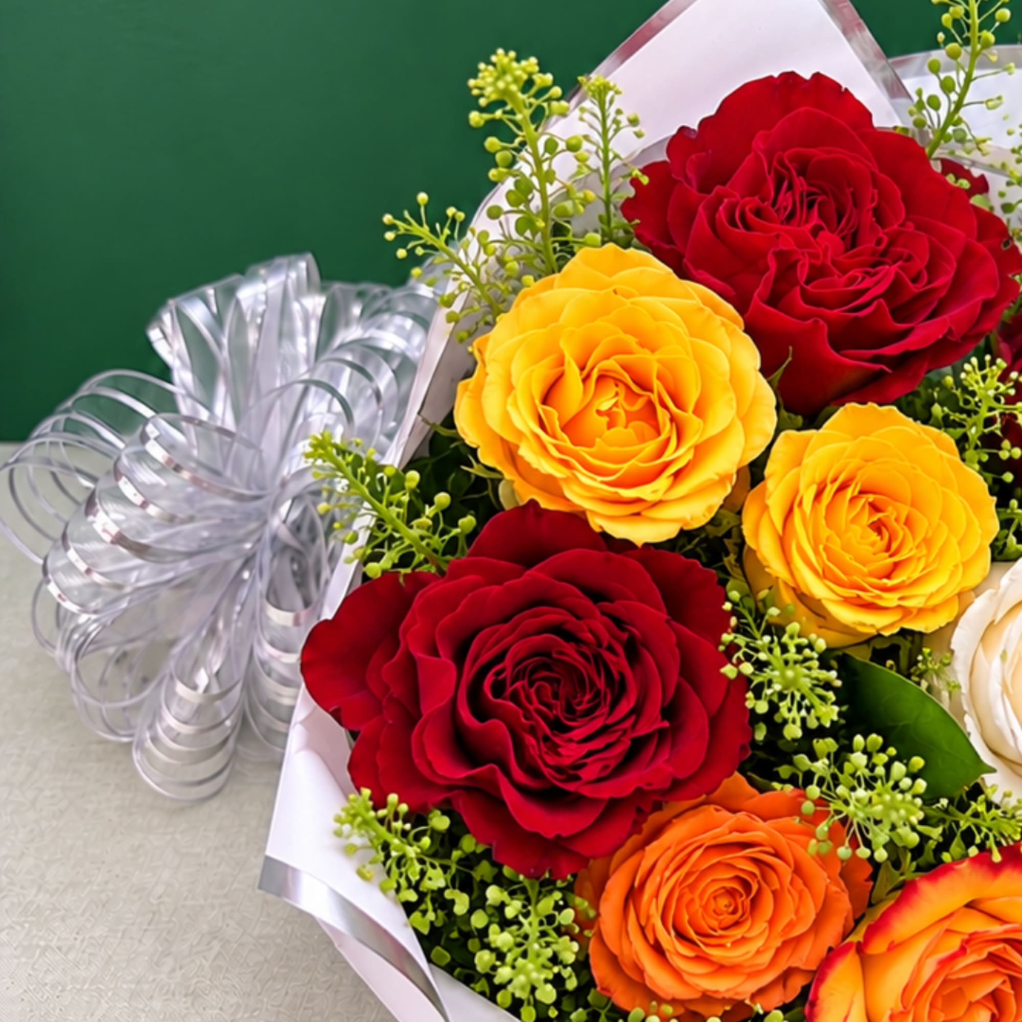 Bouquet of red, yellow, and orange roses with a silver ribbon bow