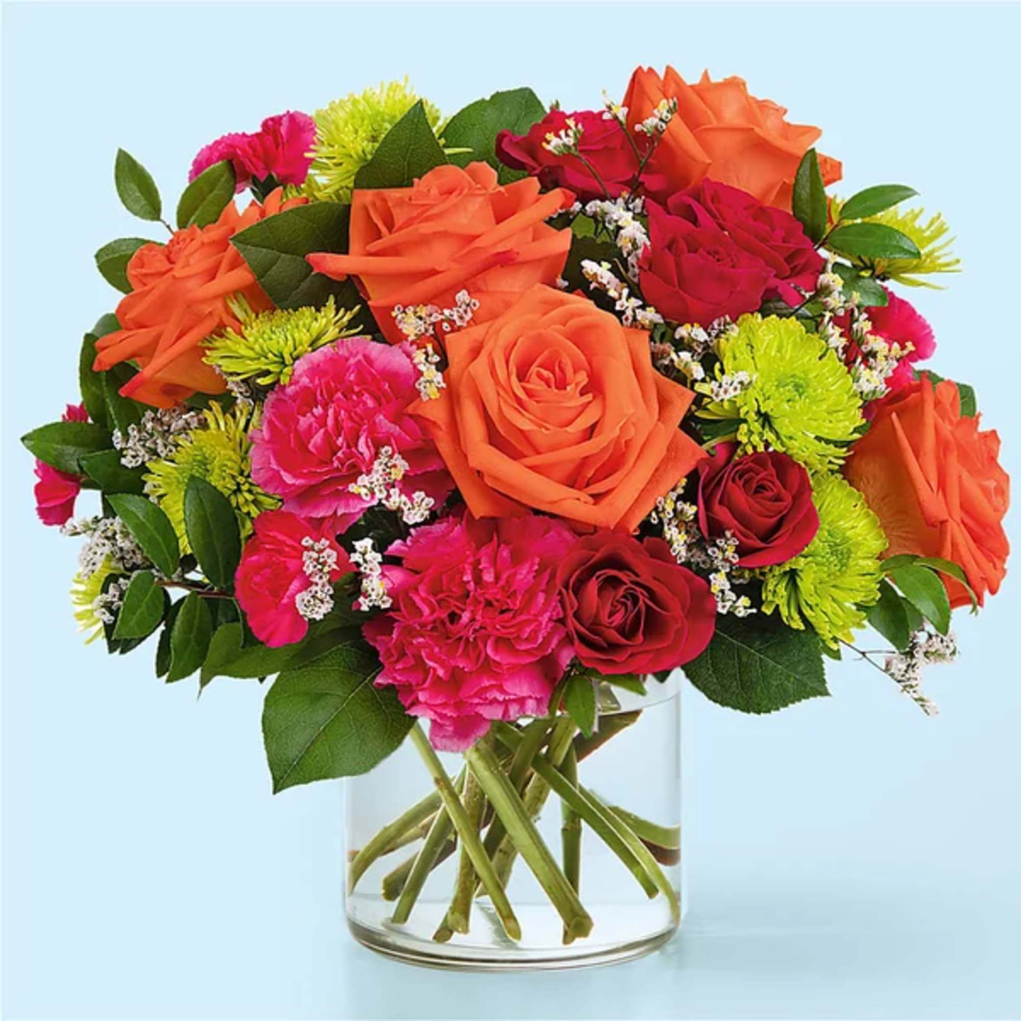 Bouquet of orange and pink roses with carnations in a clear glass vase