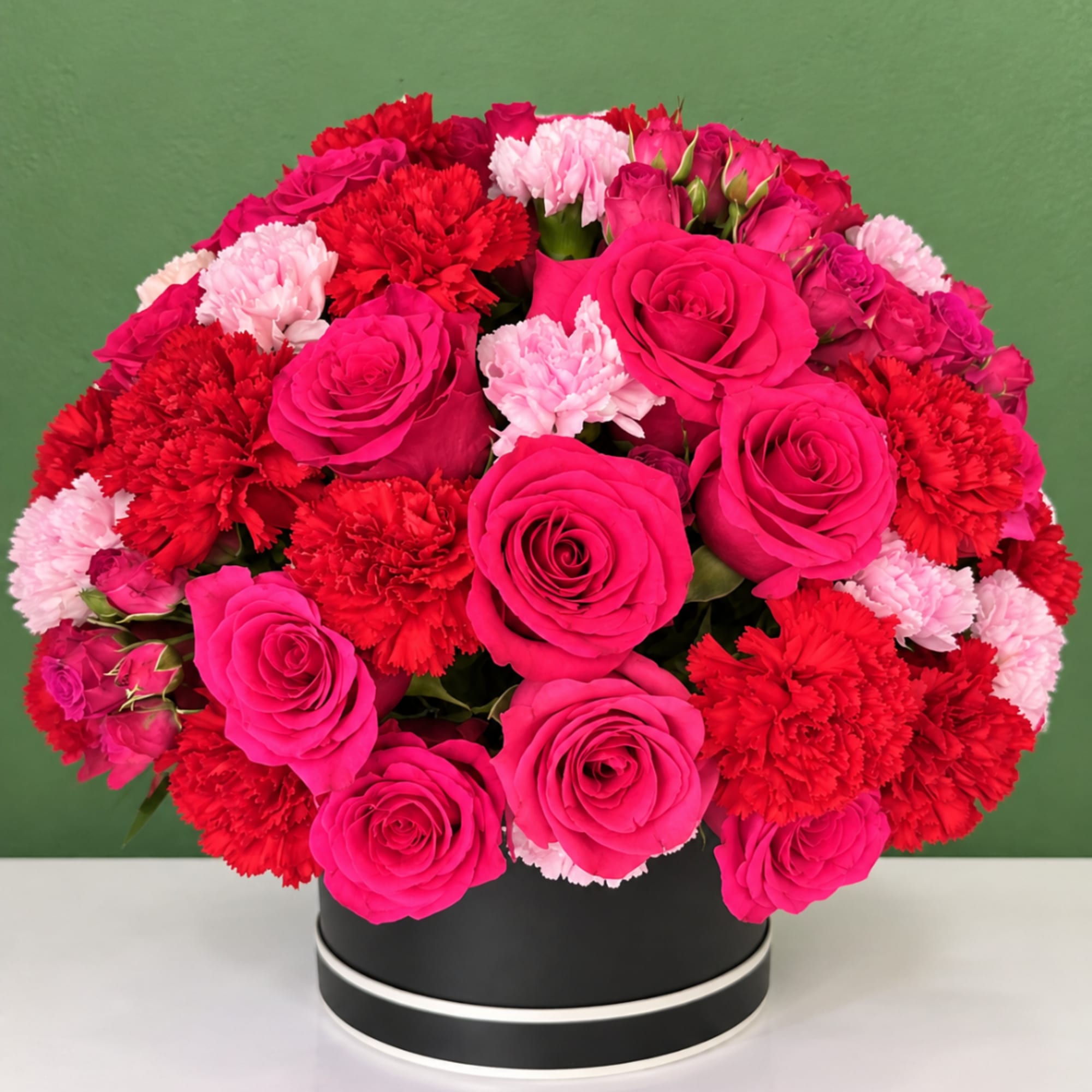Pink roses and red carnations in a black round box