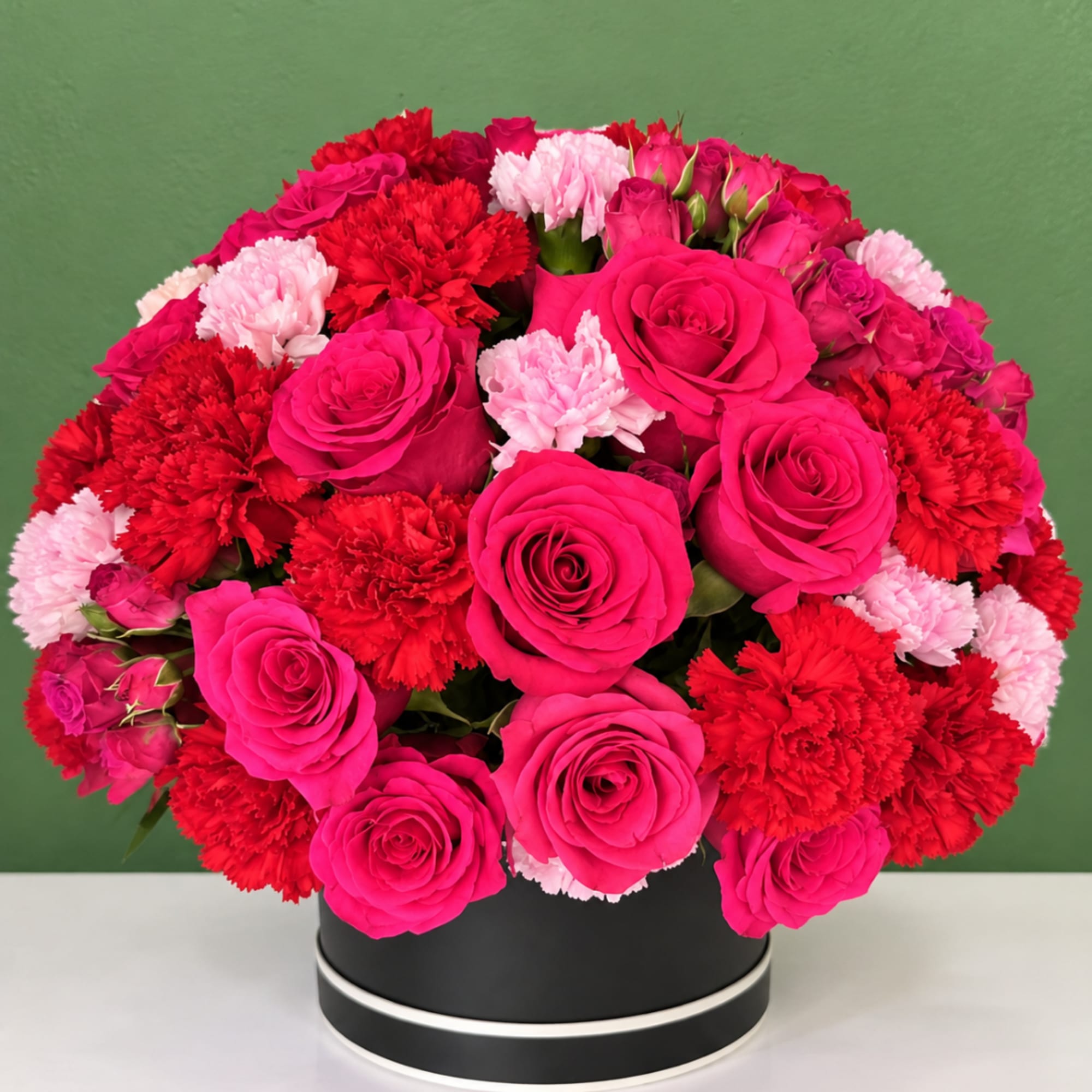 Pink and red roses with carnations in a black round box