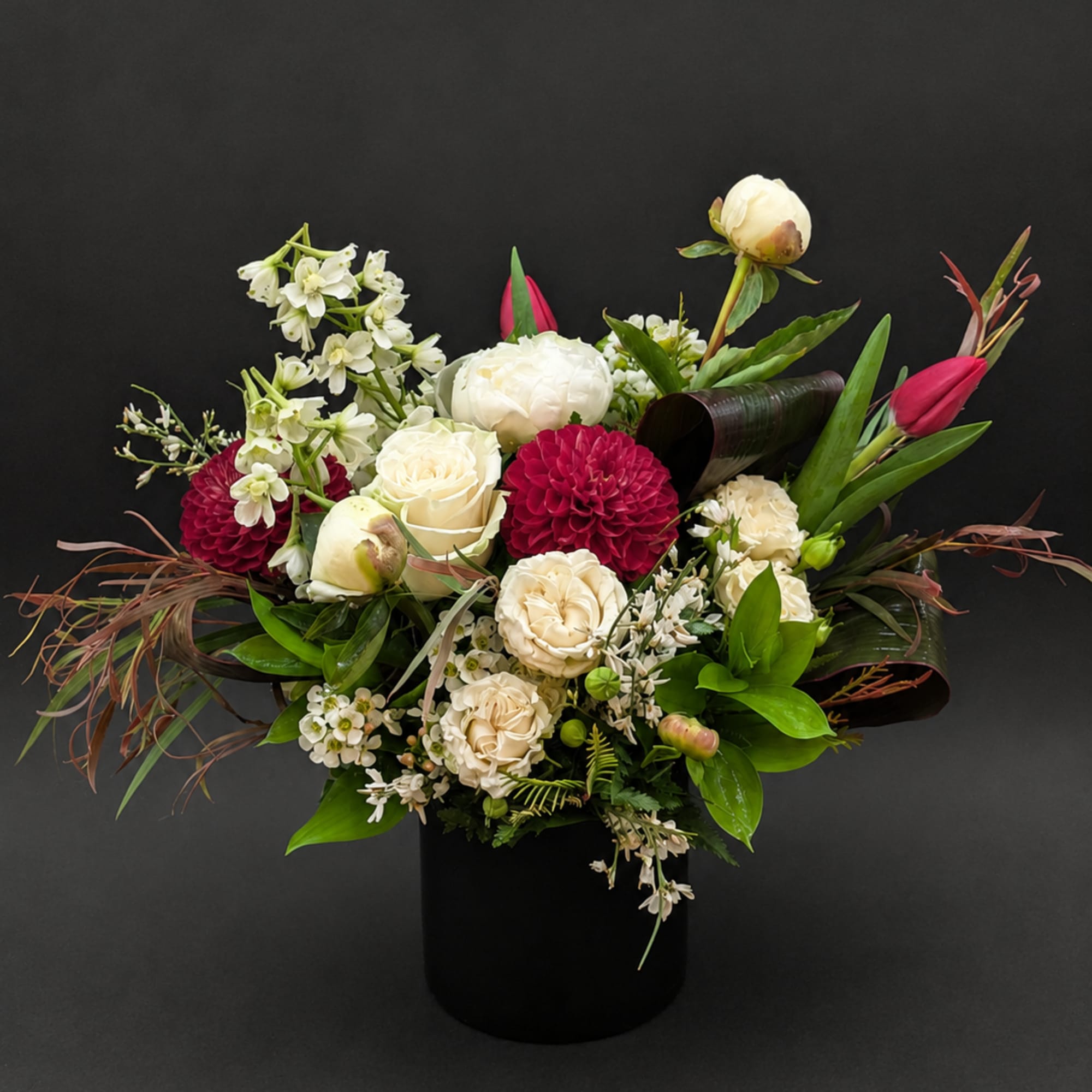 Mixed bouquet of white and deep pink flowers in a black vase