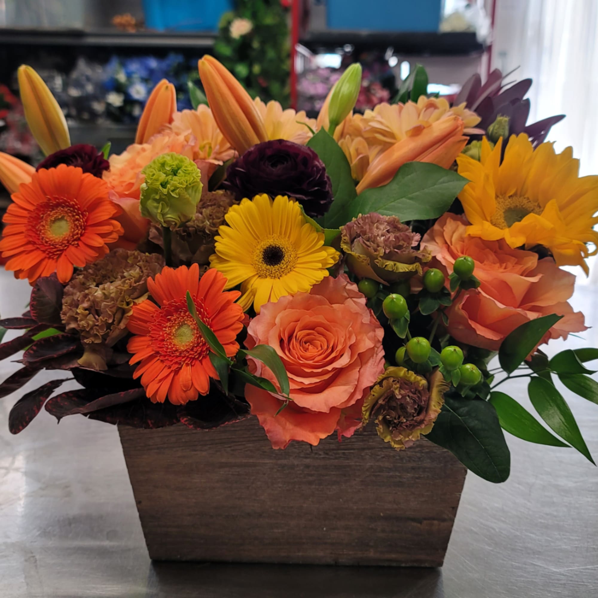 Mixed bouquet in a wooden box with orange, yellow, and peach flowers