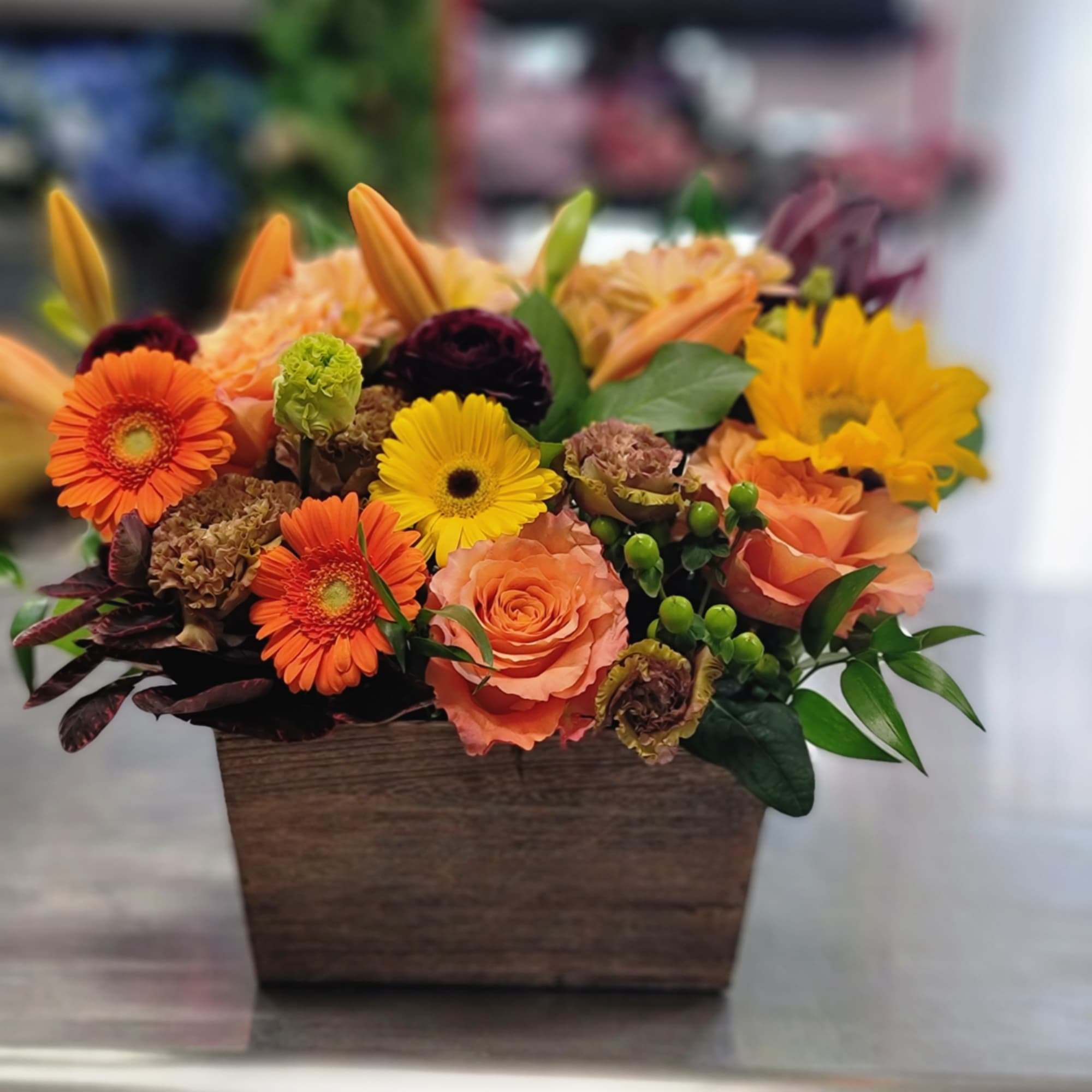 Mixed orange and yellow flowers arranged in a wooden box