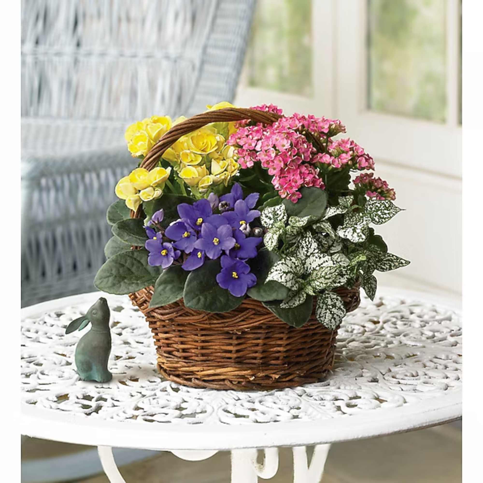 Basket of yellow, pink, and purple potted flowers with a small bunny figurine