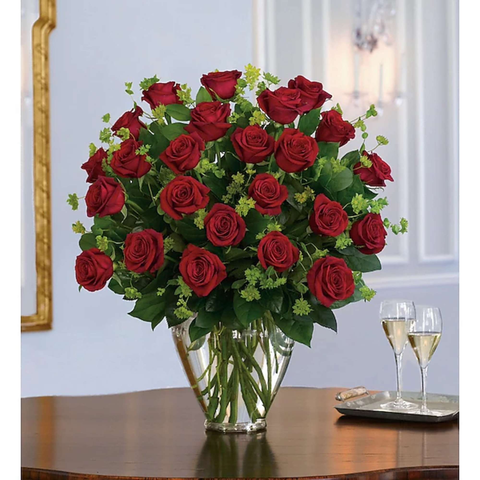 Red roses arranged in a clear glass vase with green filler