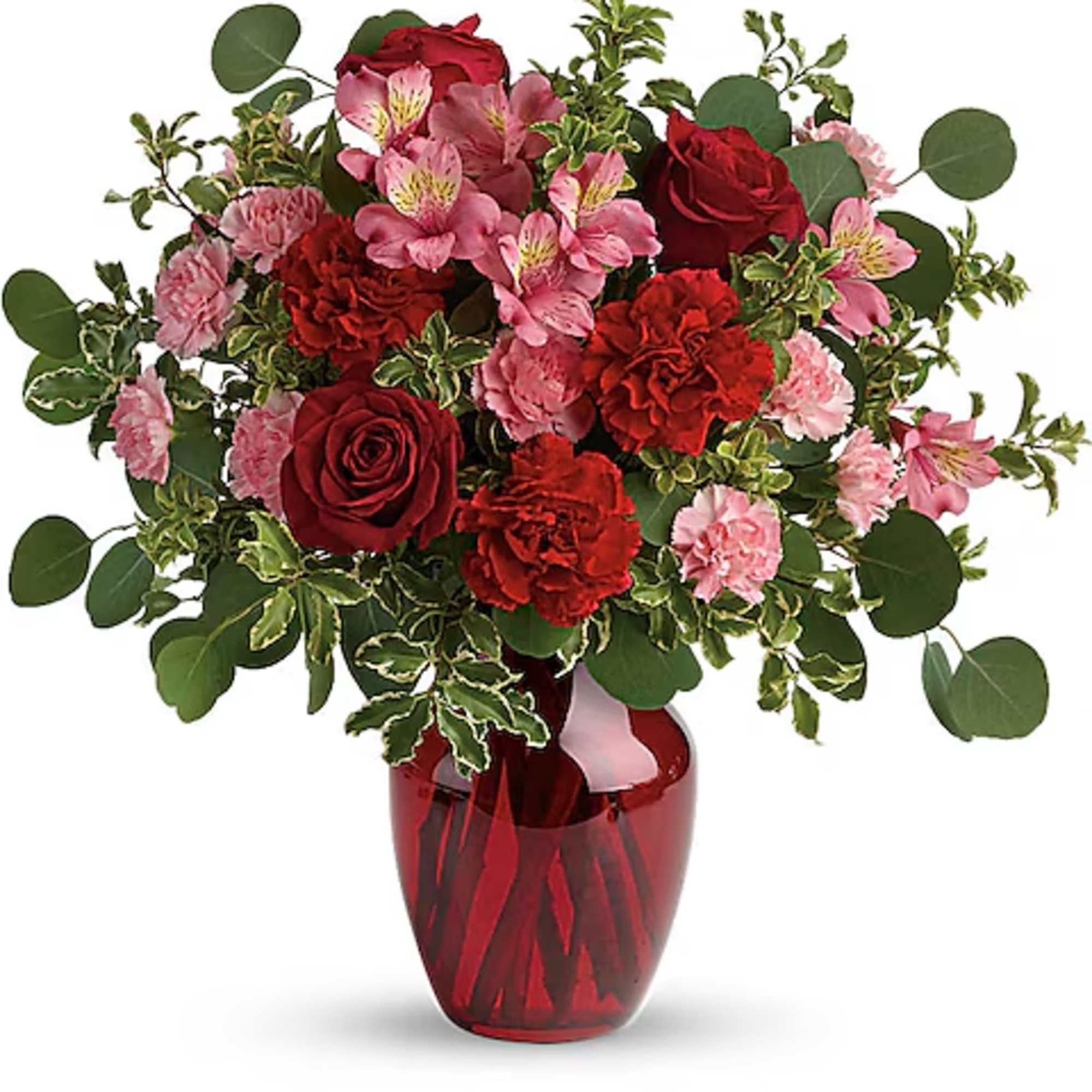 Bouquet of red roses and pink flowers in a red glass vase