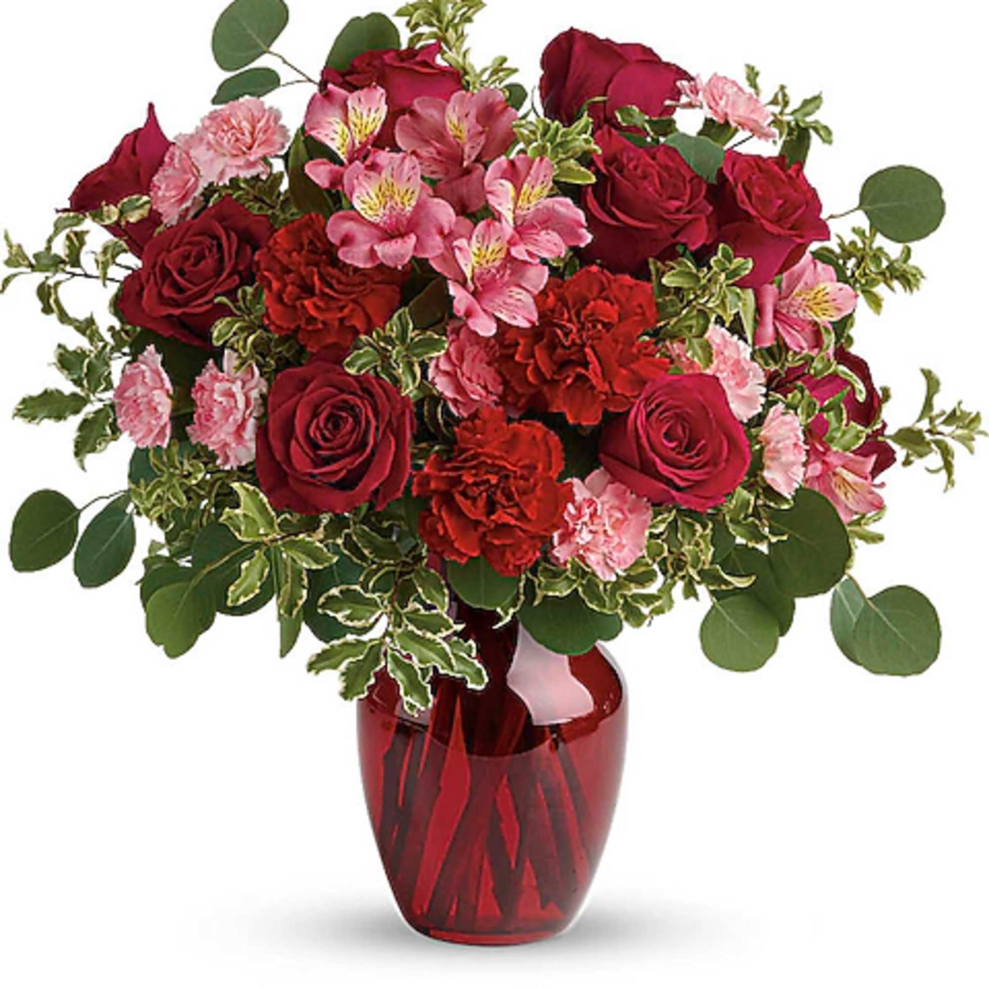 Red roses and pink flowers arranged in a red glass vase