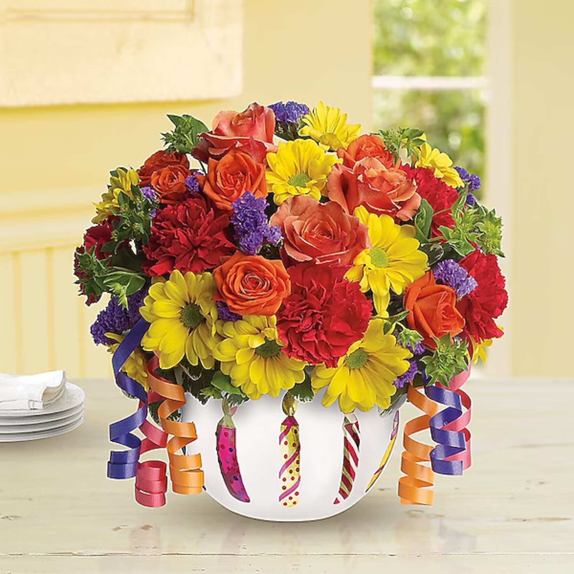 Colorful bouquet of roses, daisies, and carnations in a white vase with ribbon curls