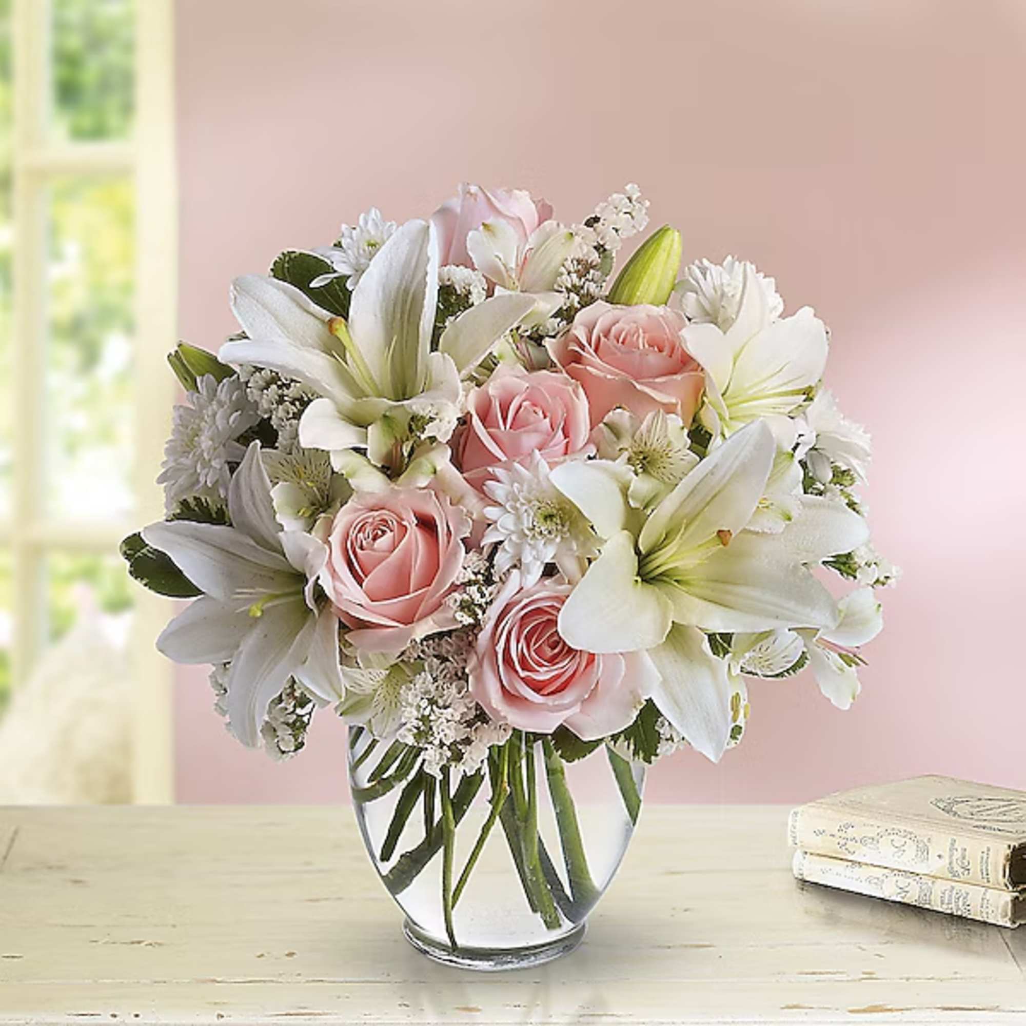 Pink roses and white lilies arranged in a clear glass vase