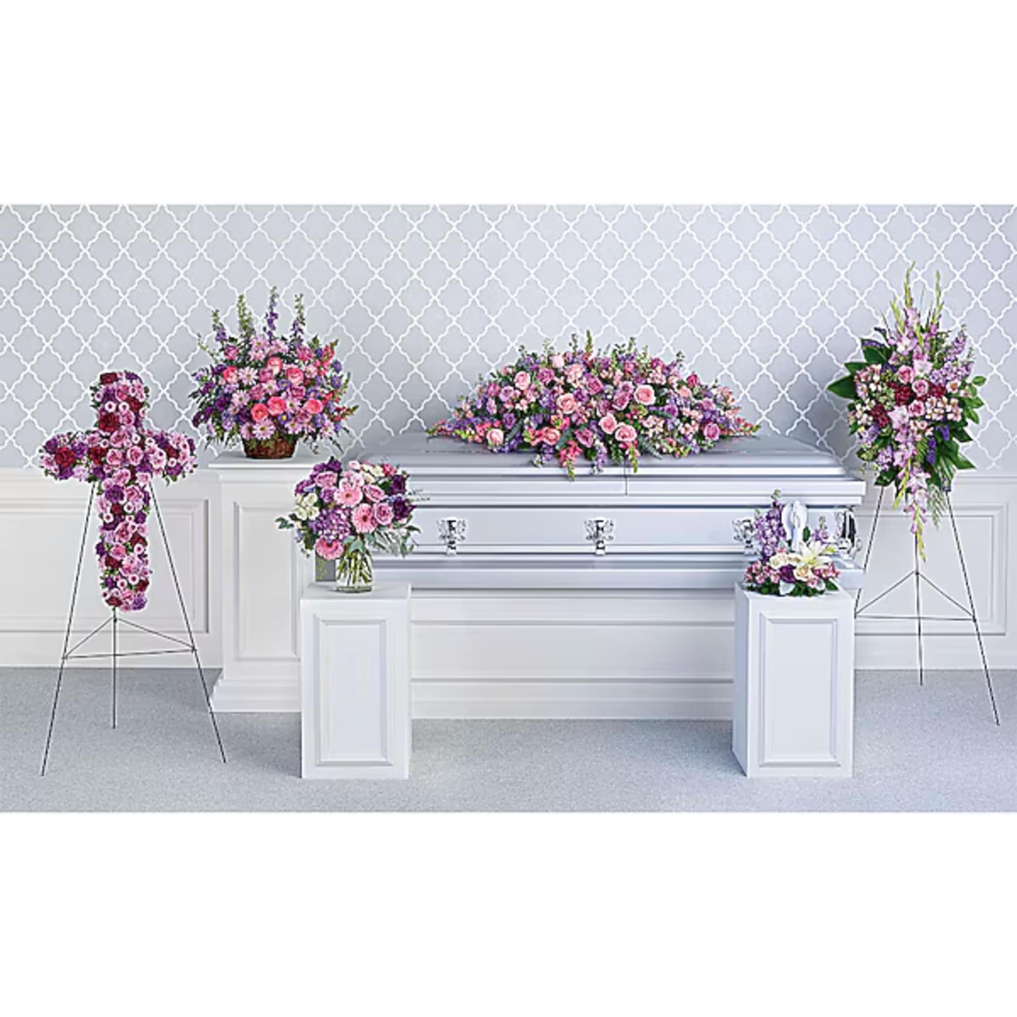 Floral funeral display with pink and purple arrangements around a white casket