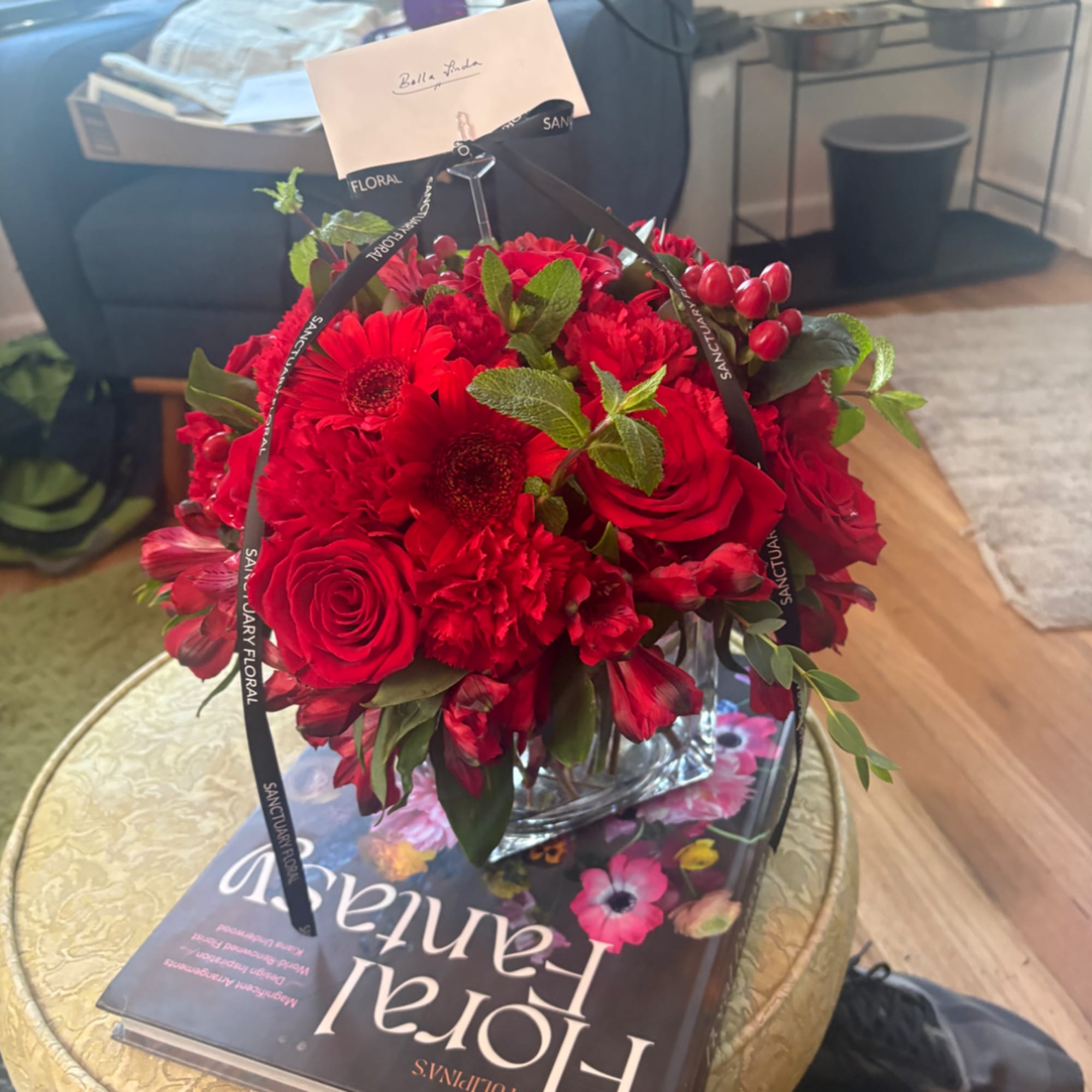 Red rose and gerbera bouquet in a clear glass vase with ribbon