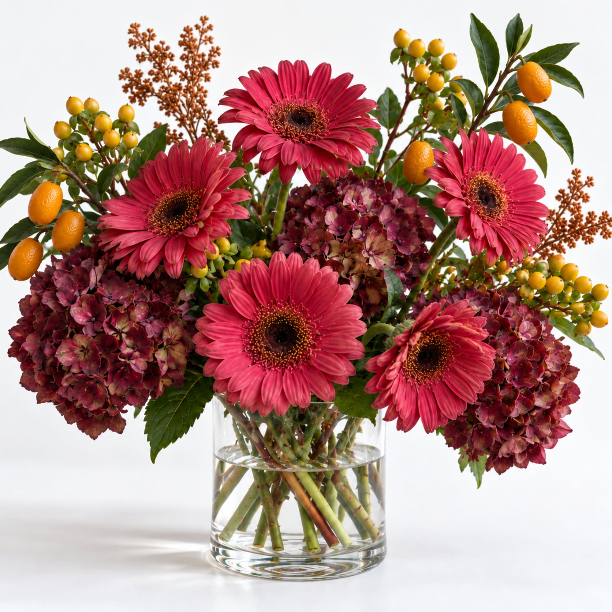 Pink gerbera daisies and burgundy hydrangeas in a clear glass vase