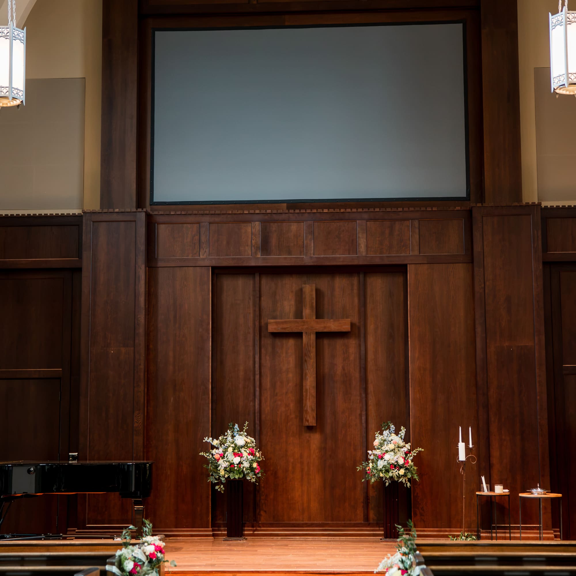 Church sanctuary with floral arrangements on pedestals and pew ends