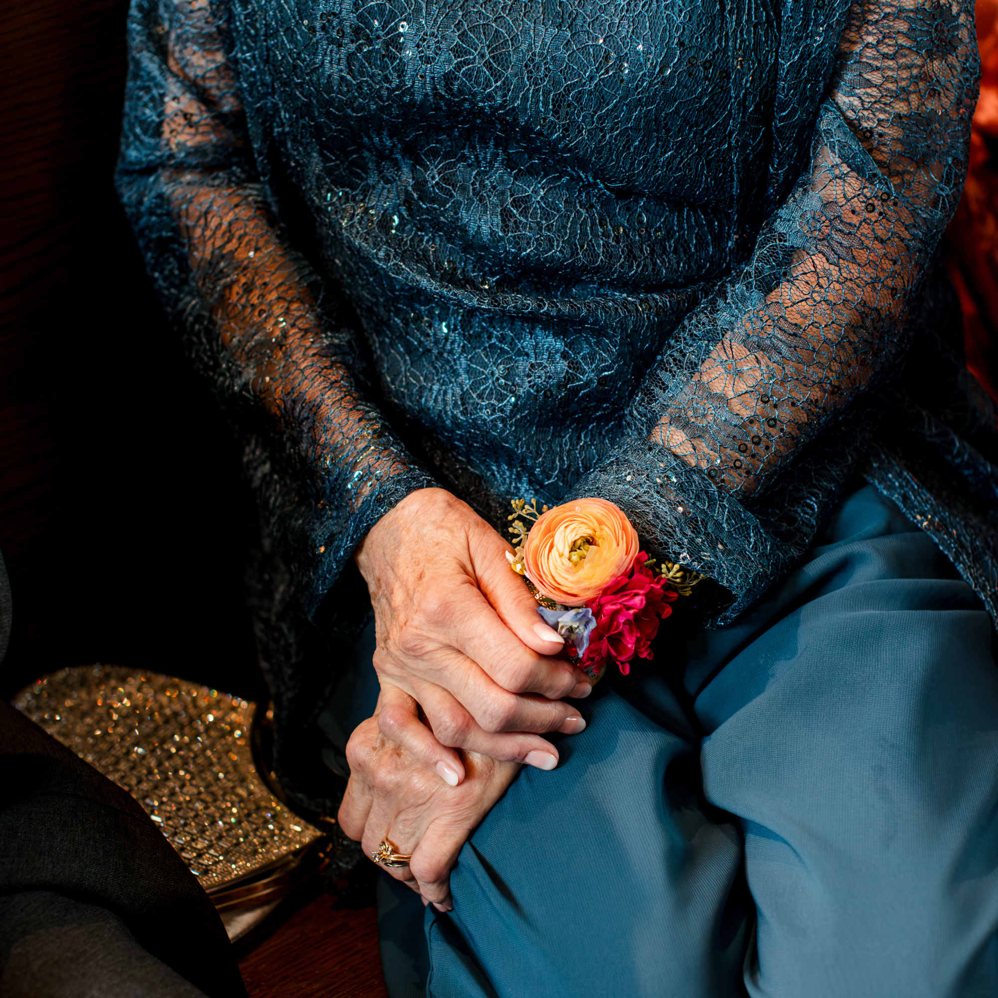Woman in a teal lace dress holding a small floral corsage