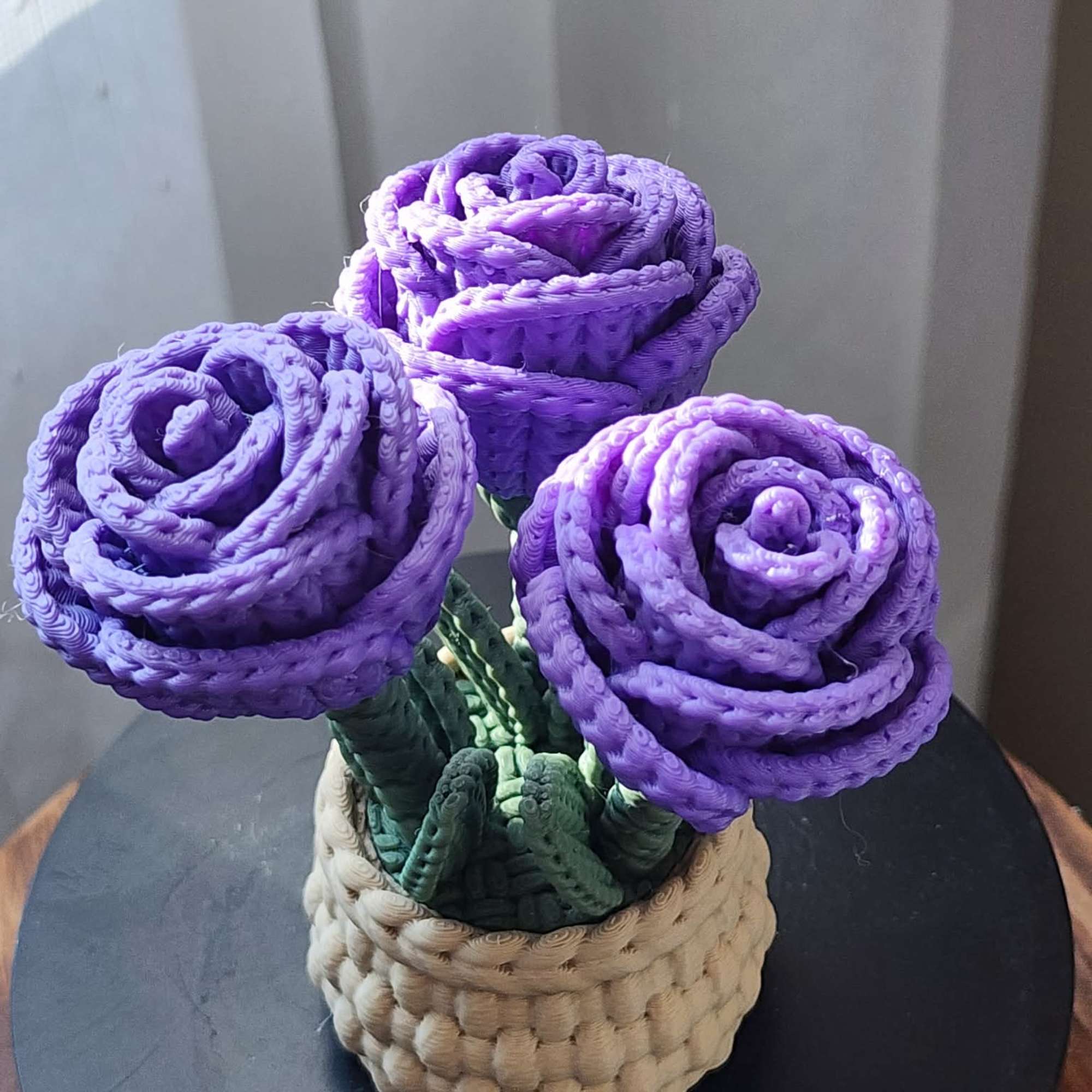 Three purple woven roses in a small basket