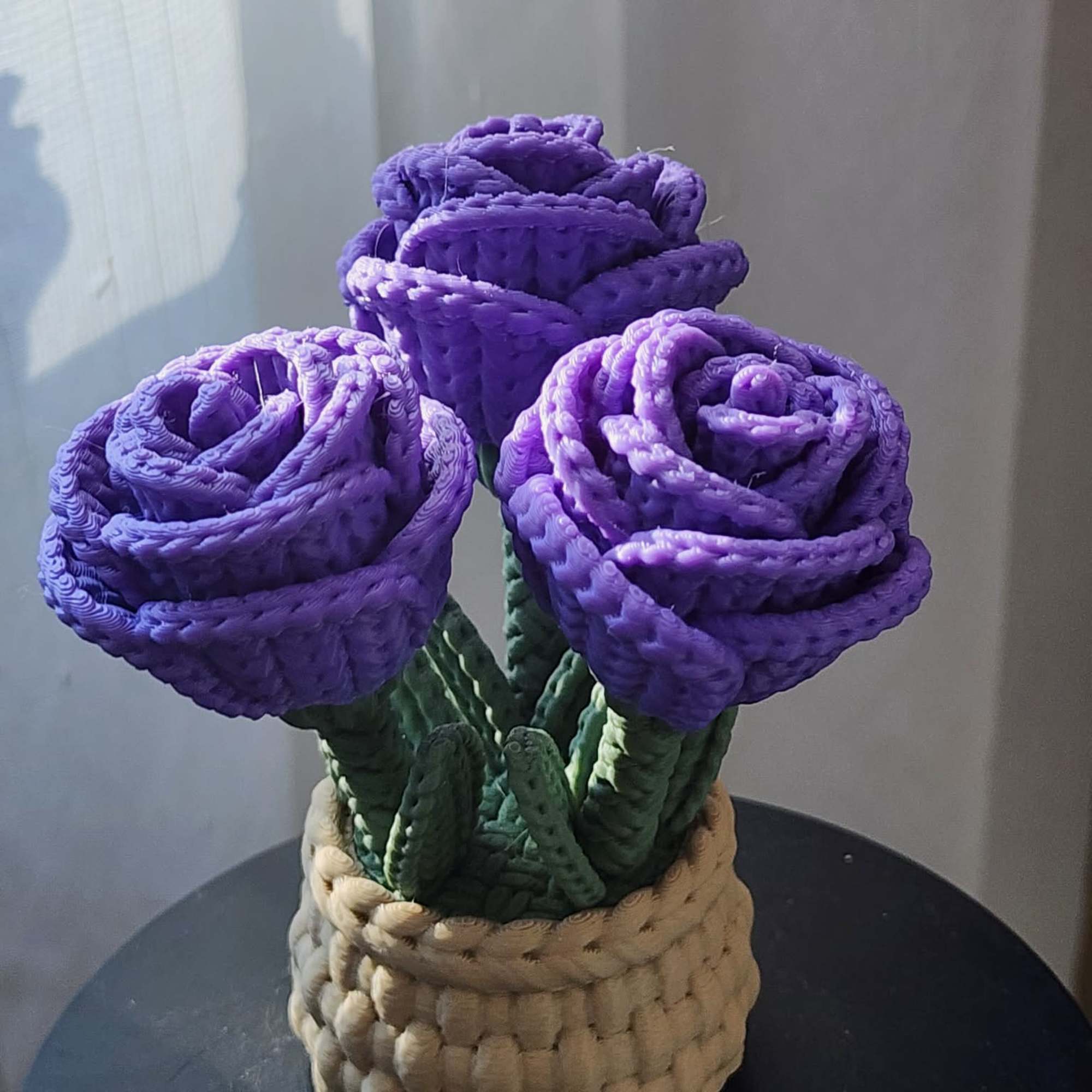 Three purple roses in a woven basket
