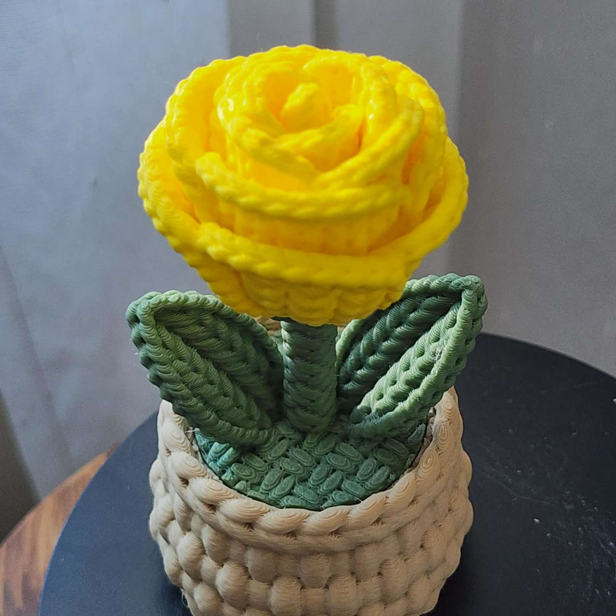 Yellow rose-shaped flower in a woven basket planter