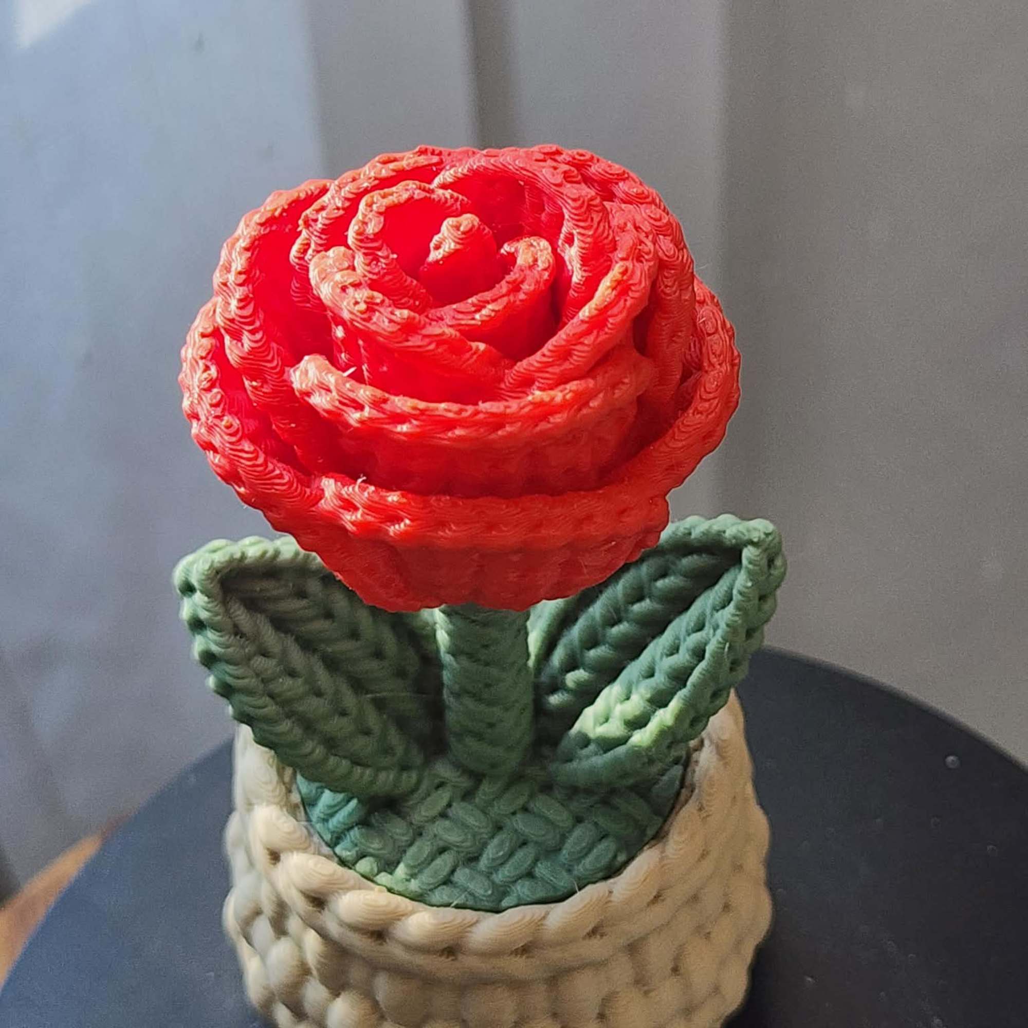 Red rose-shaped decorative item in a woven basket base