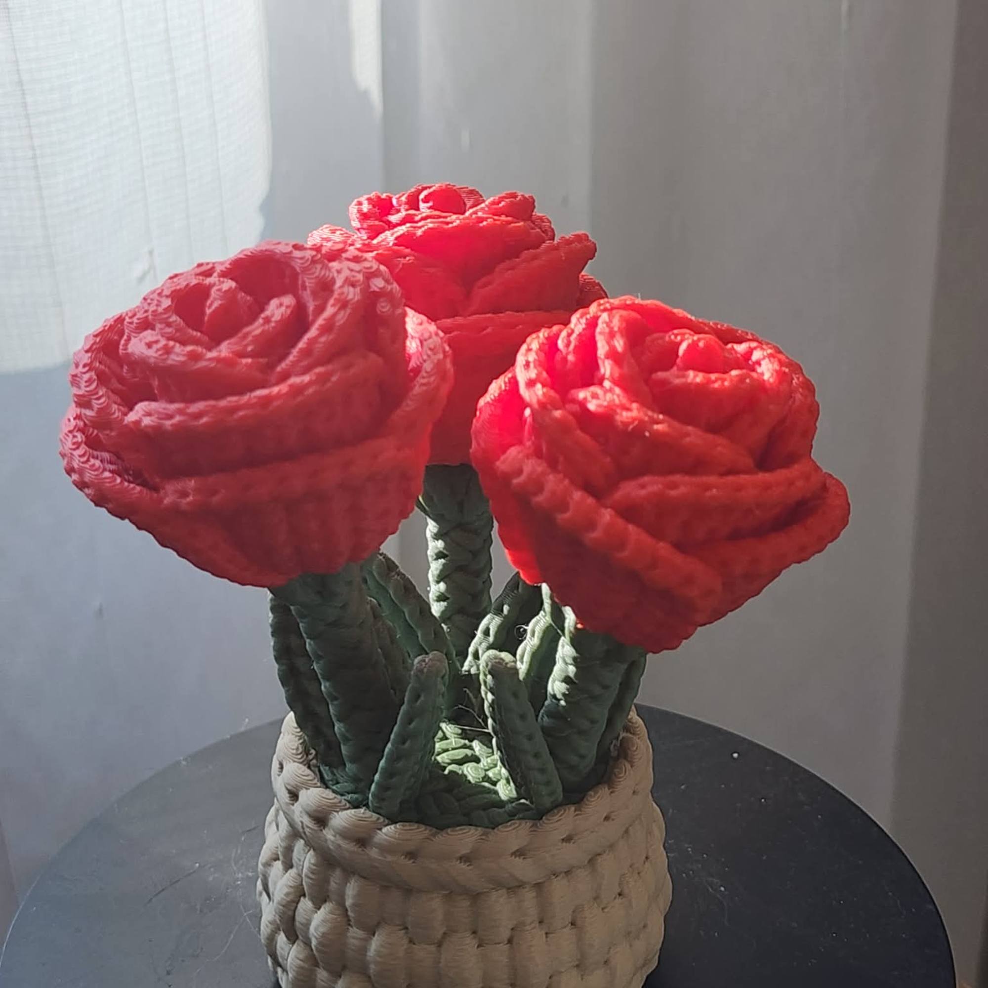 Three red flowers in a woven basket planter