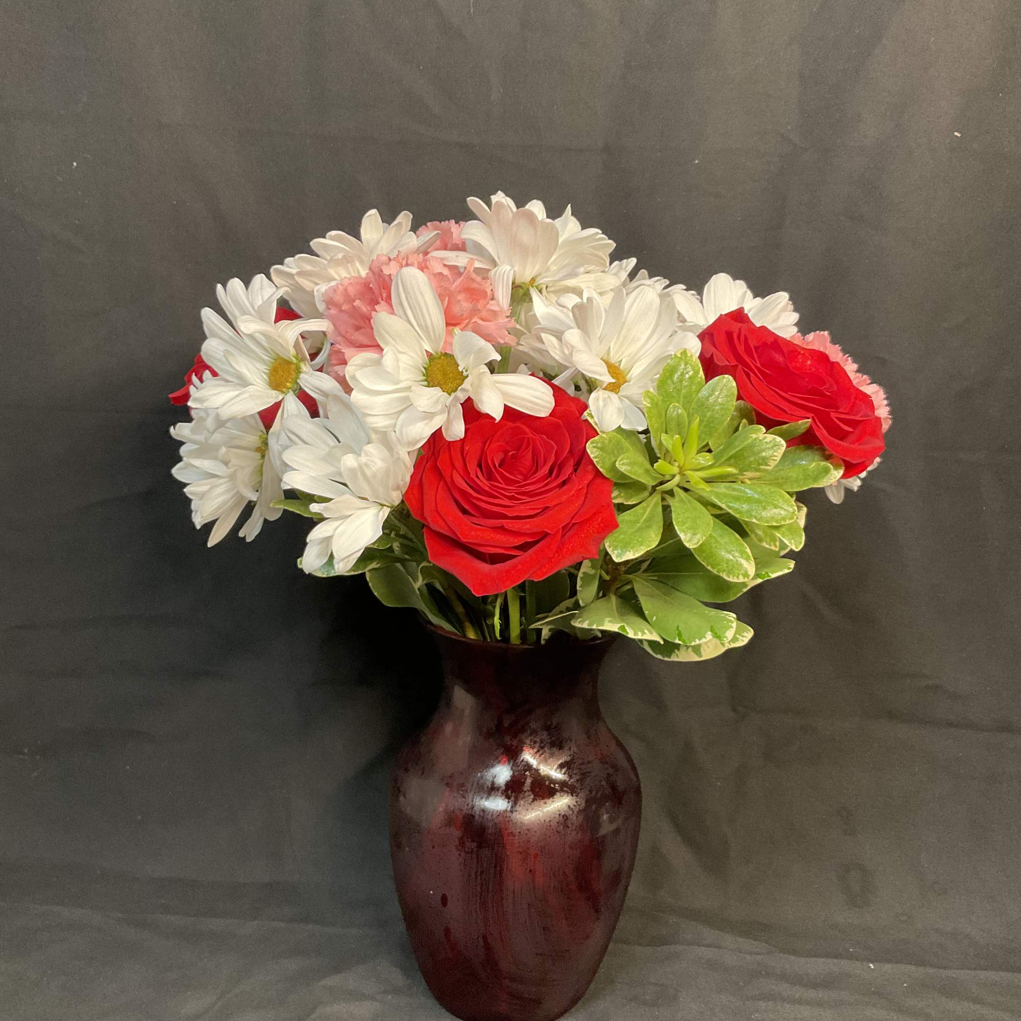 Red roses and white daisies in a burgundy vase