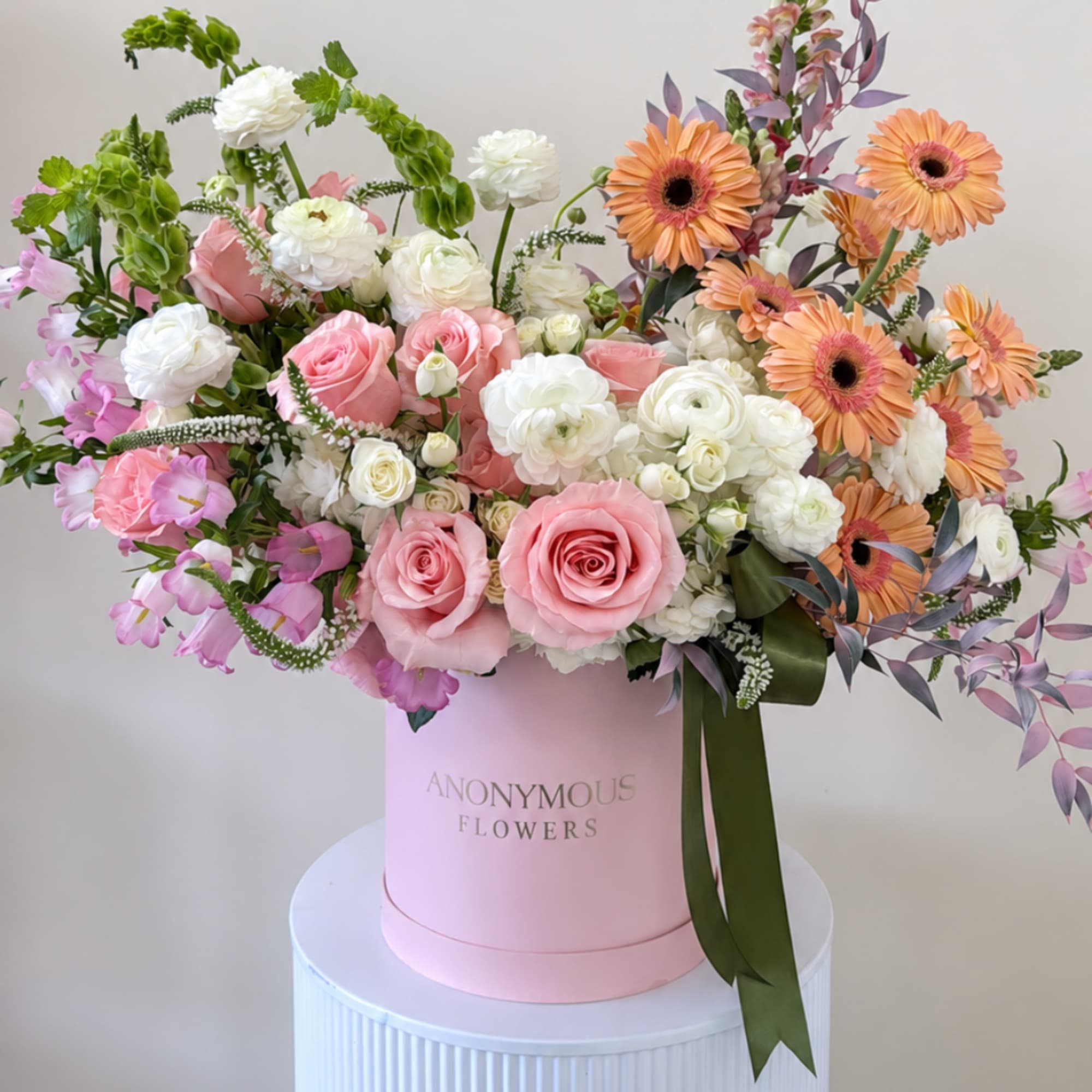 Pink and white mixed bouquet in a pink hatbox with orange daisies