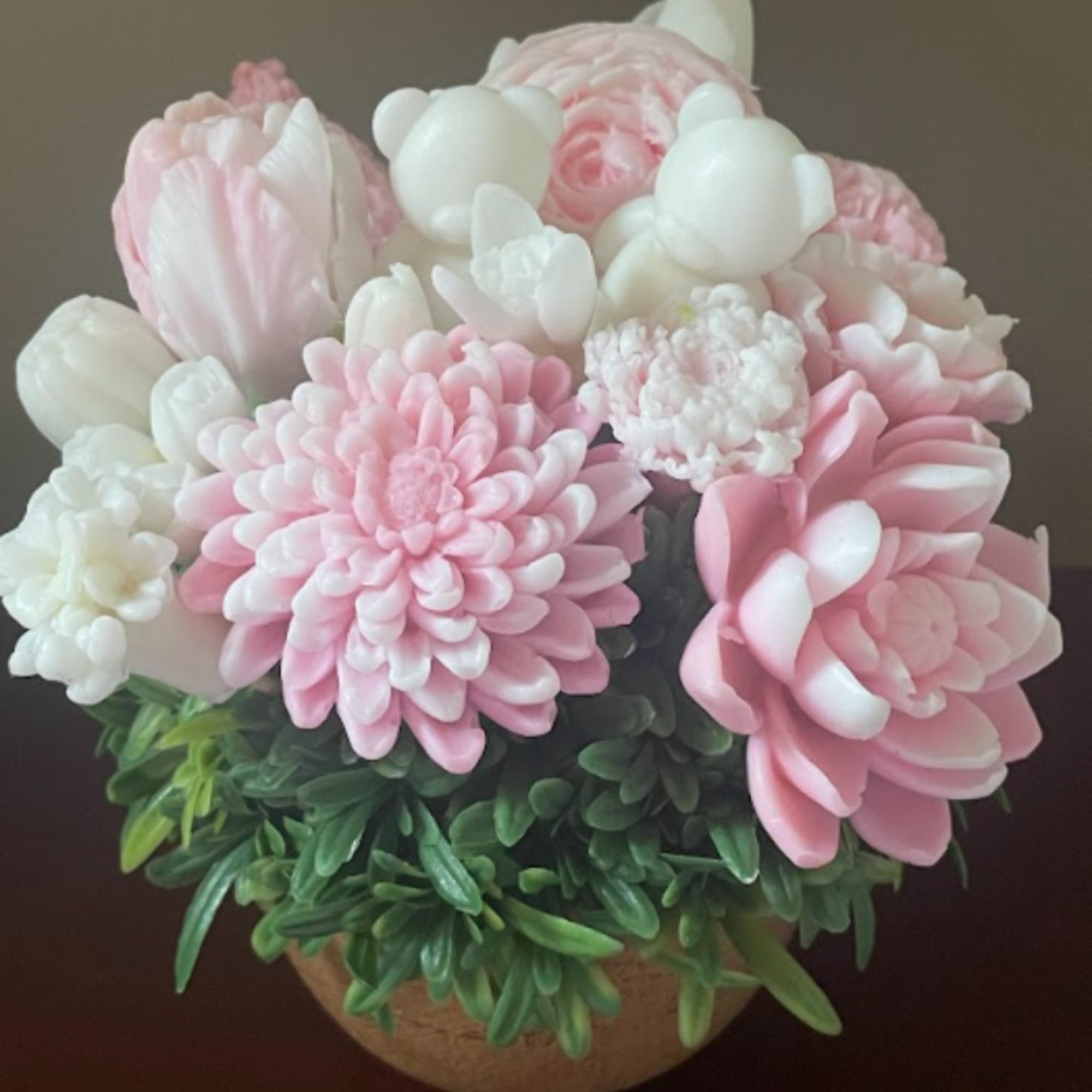 Pink and white flower arrangement in a round pot with green foliage