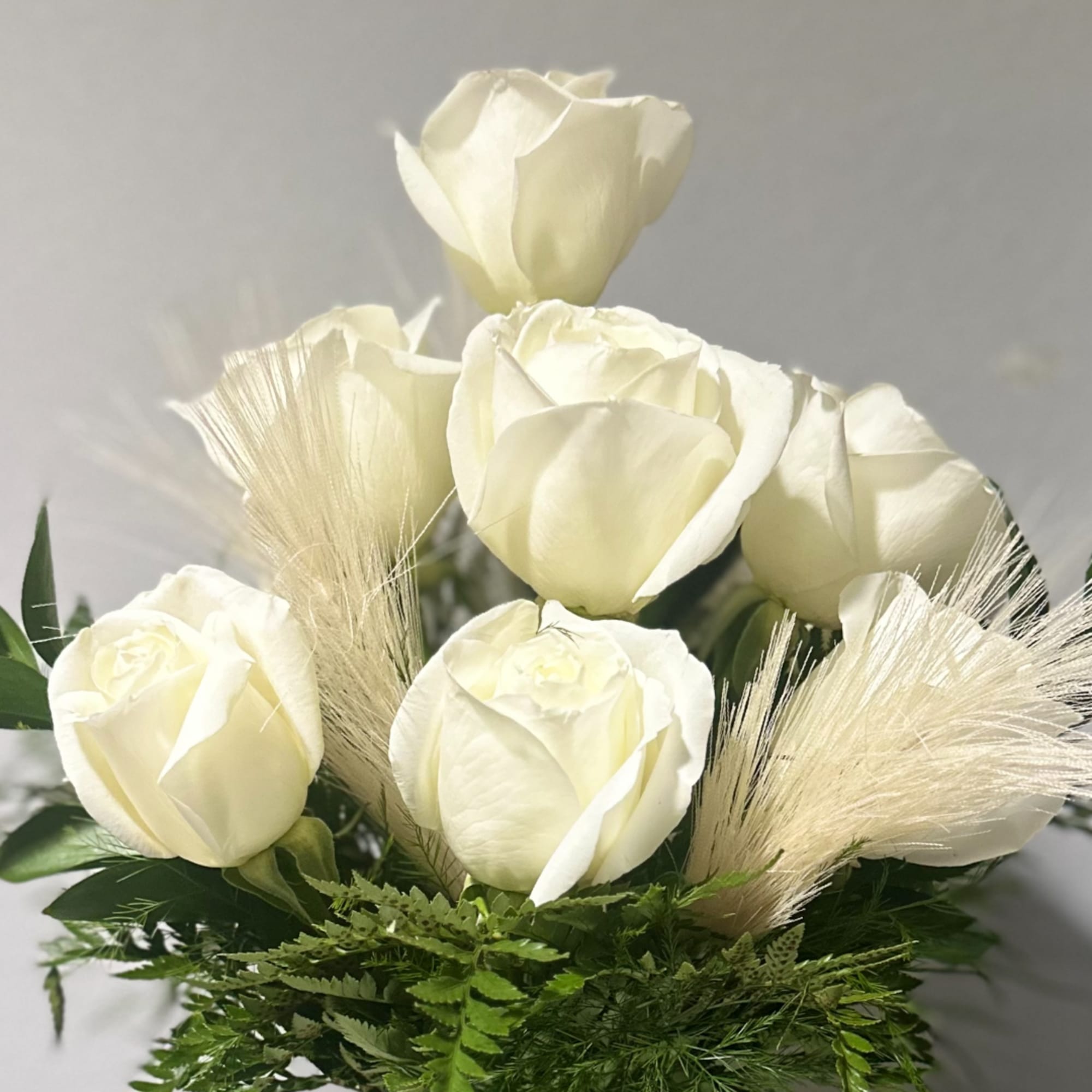 White rose bouquet with feathery beige accents and green foliage