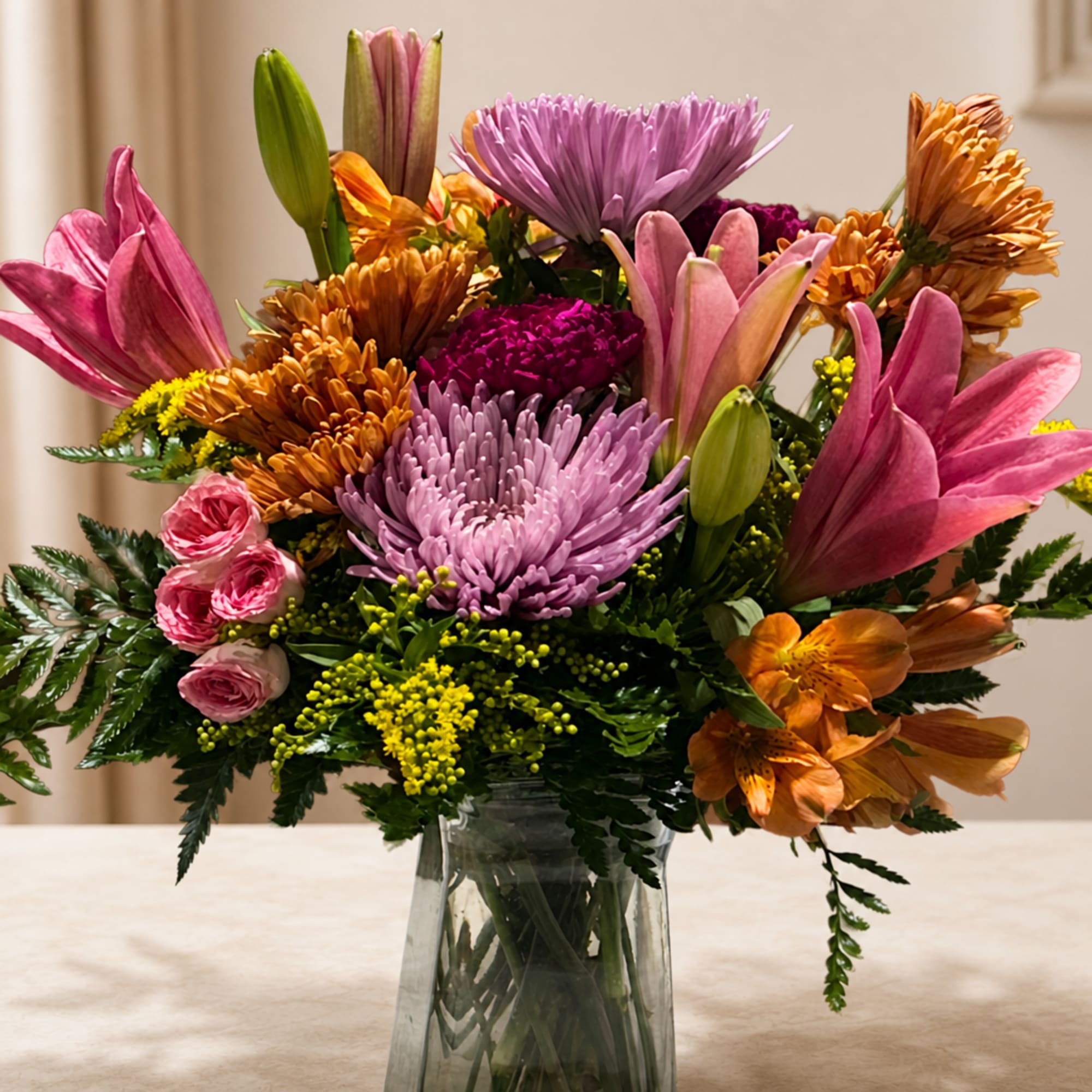Mixed bouquet of pink, purple, and orange flowers in a clear glass vase