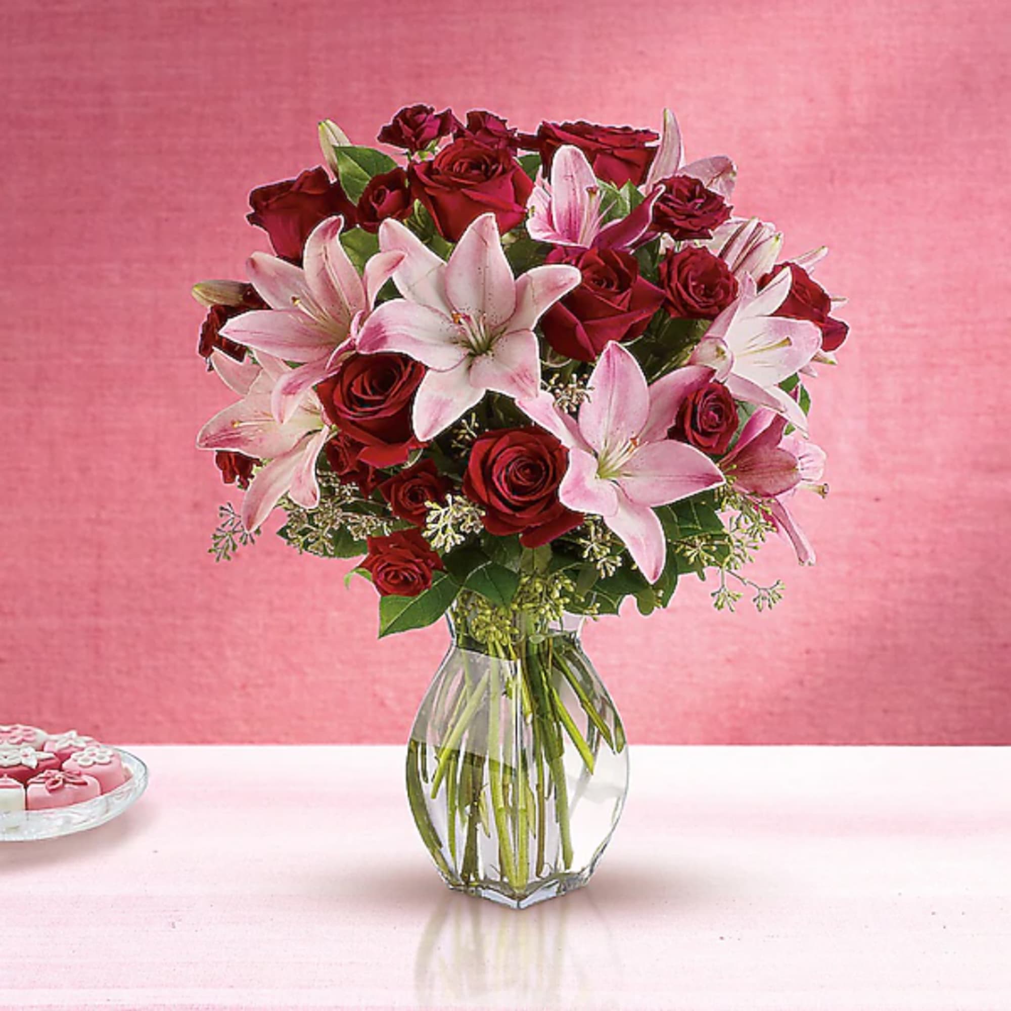 Bouquet of red roses and pink lilies in a clear glass vase