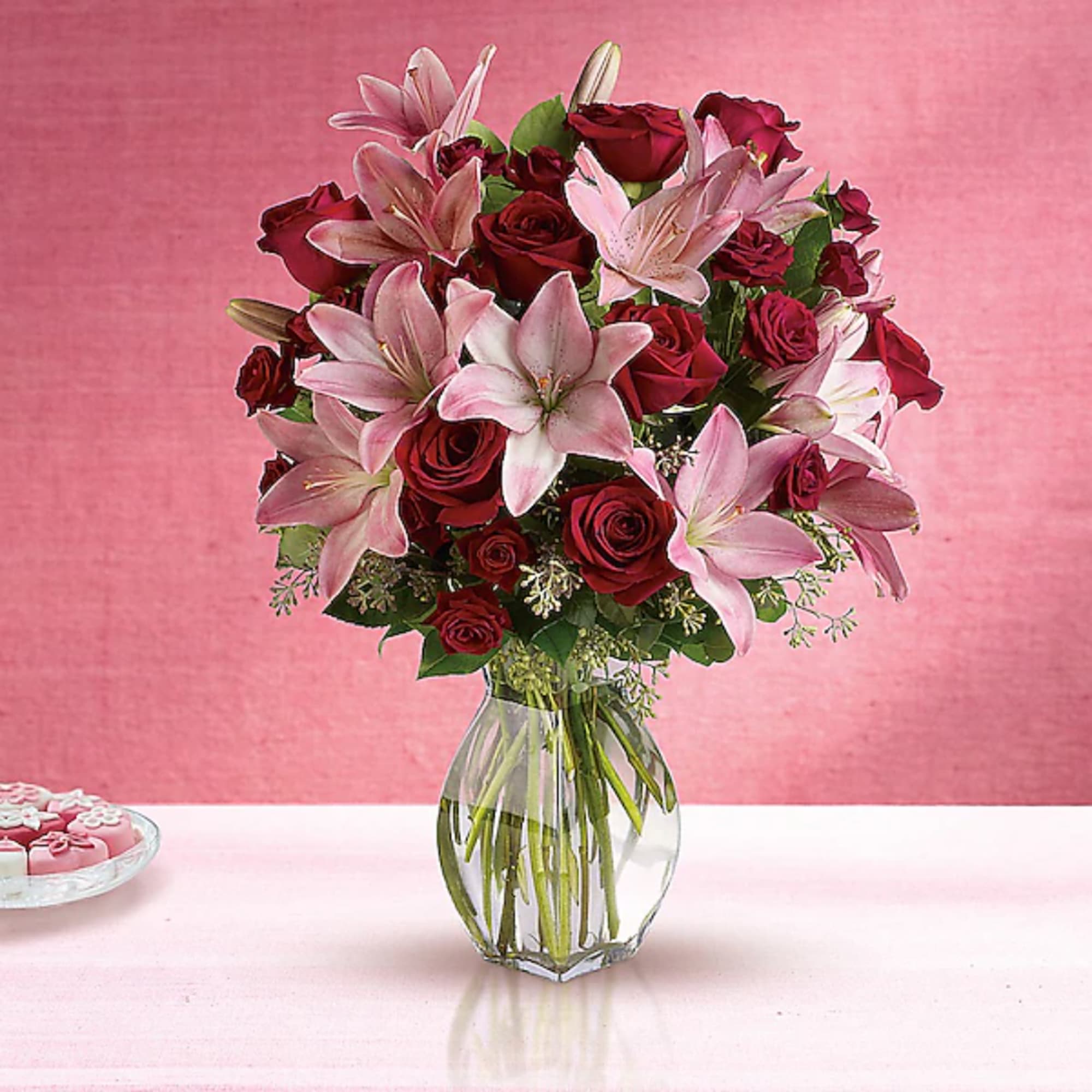 Bouquet of red roses and pink lilies in a clear glass vase, photo 2 of 2