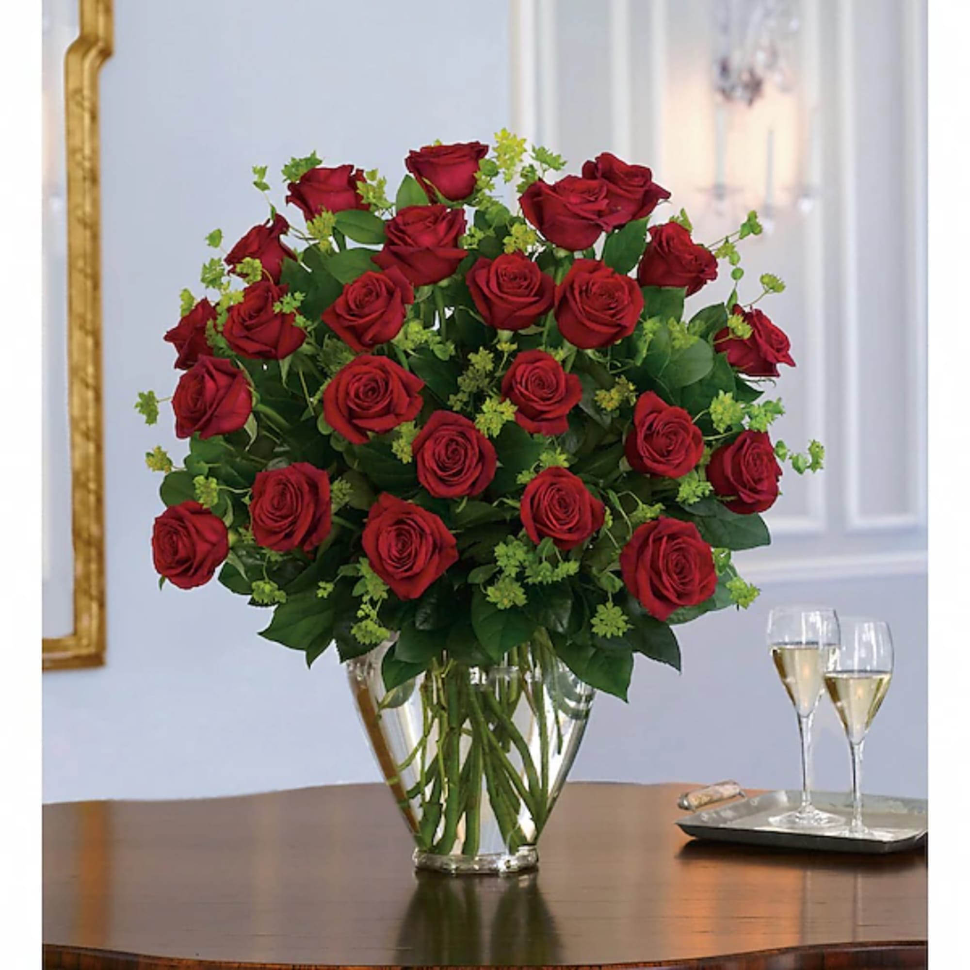 Red roses arranged in a clear glass vase on a table