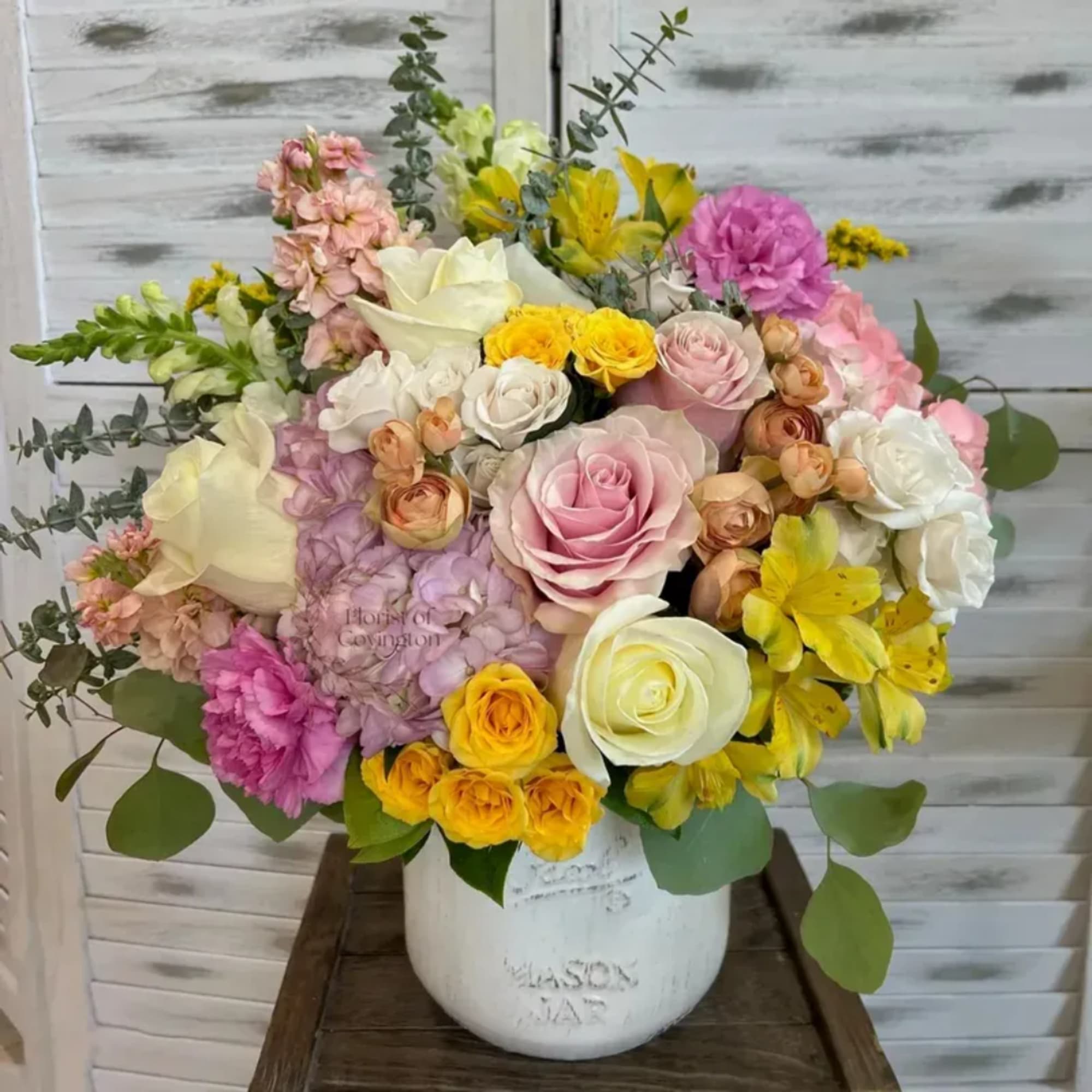 Mixed bouquet of roses, carnations, and alstroemeria in a white vase
