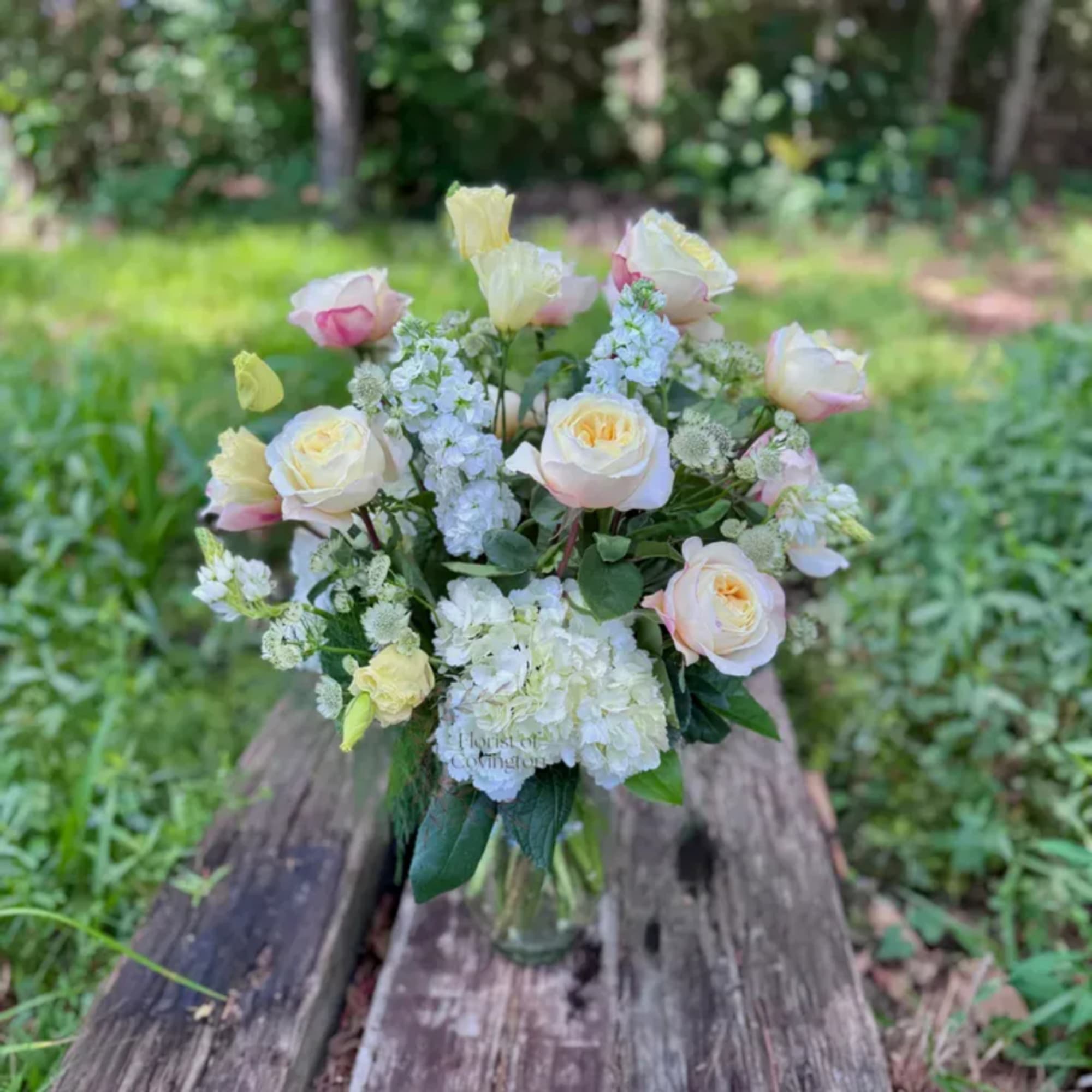 Bouquet of pale roses and white flowers in a clear glass vase
