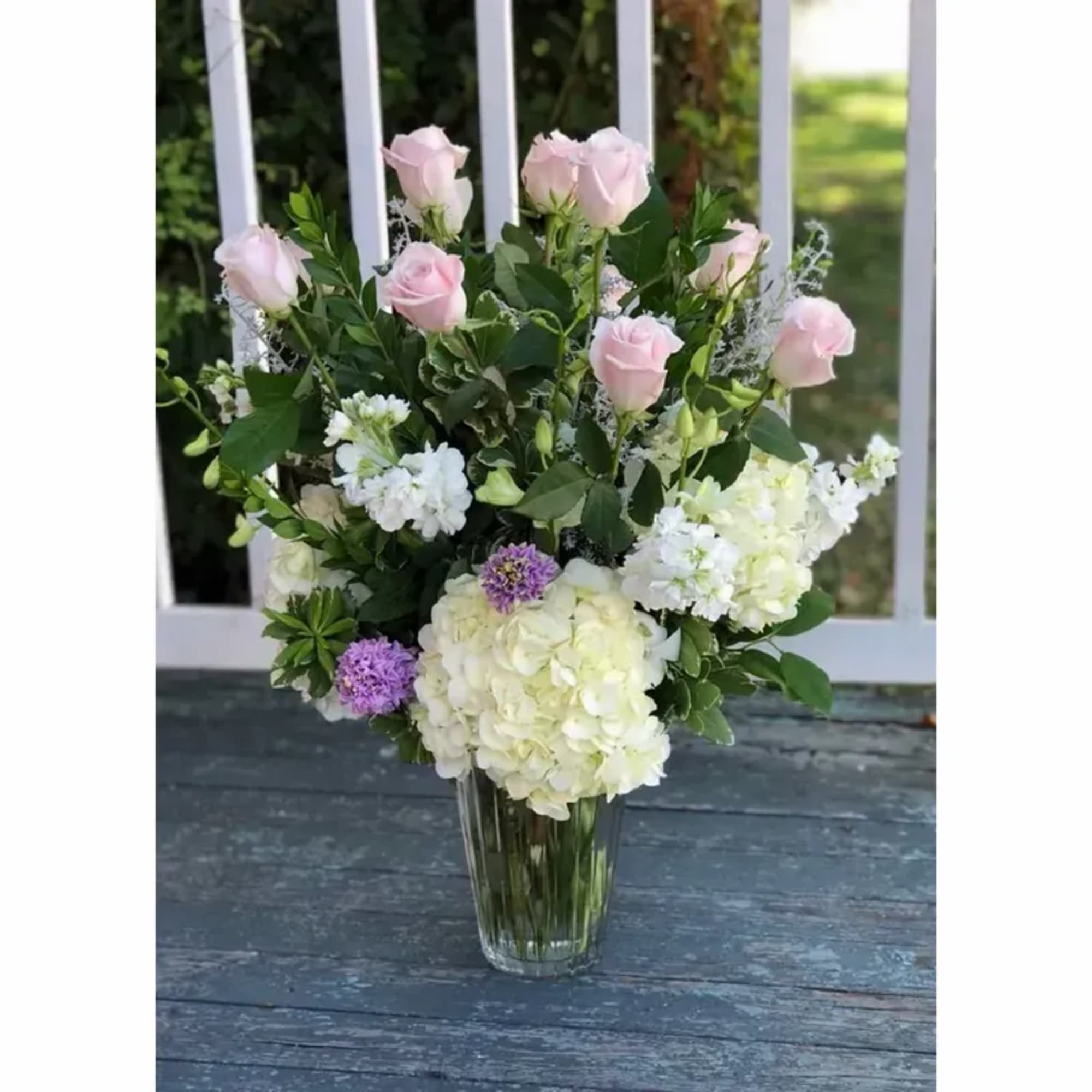 Pink roses and white hydrangeas arranged in a clear glass vase