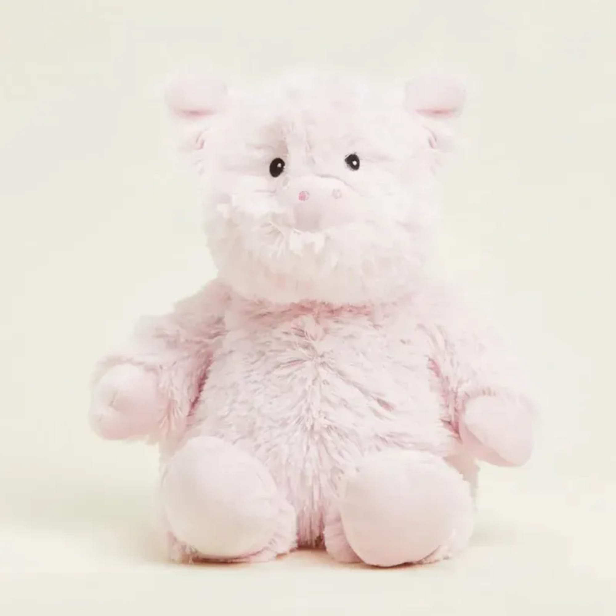 Pink plush pig toy sitting against a plain background