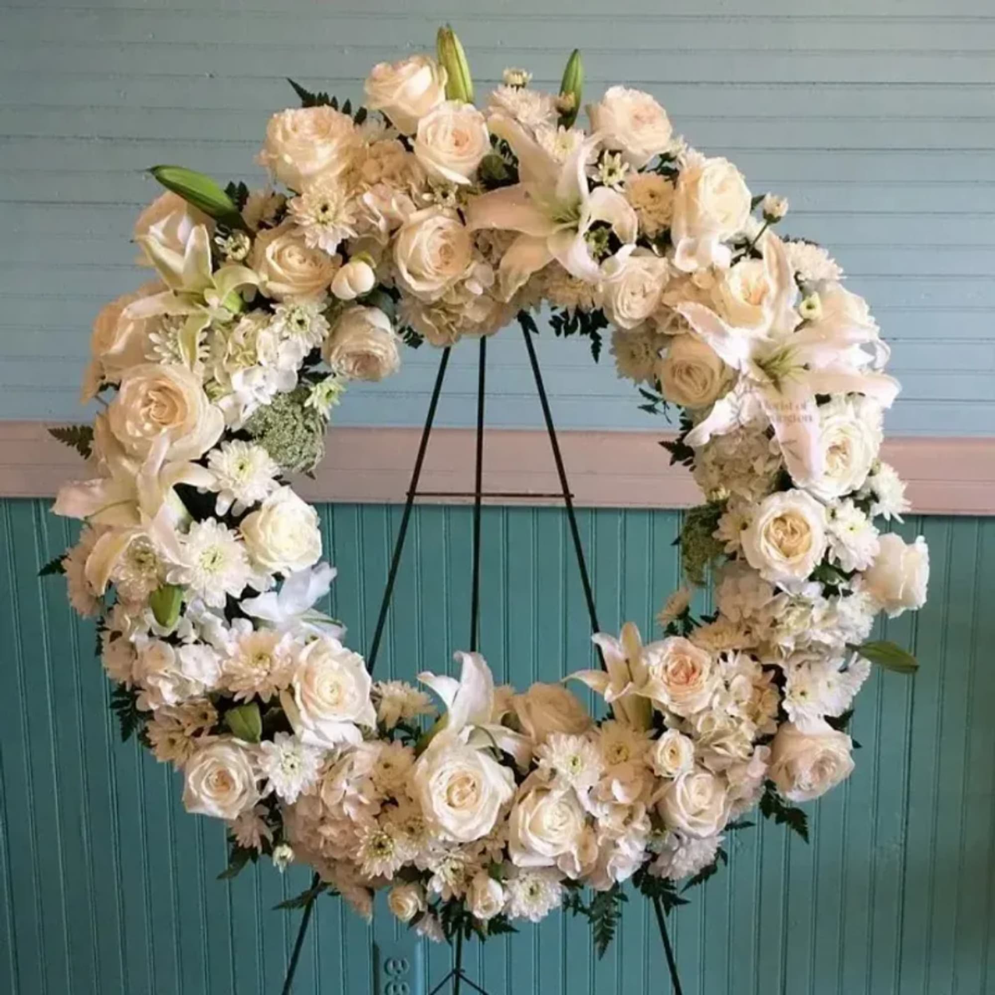 Large white floral wreath on a black stand