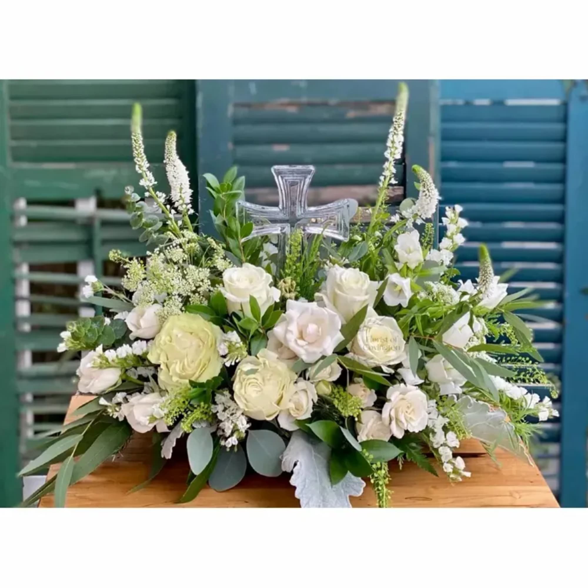 White rose arrangement with a clear cross centerpiece
