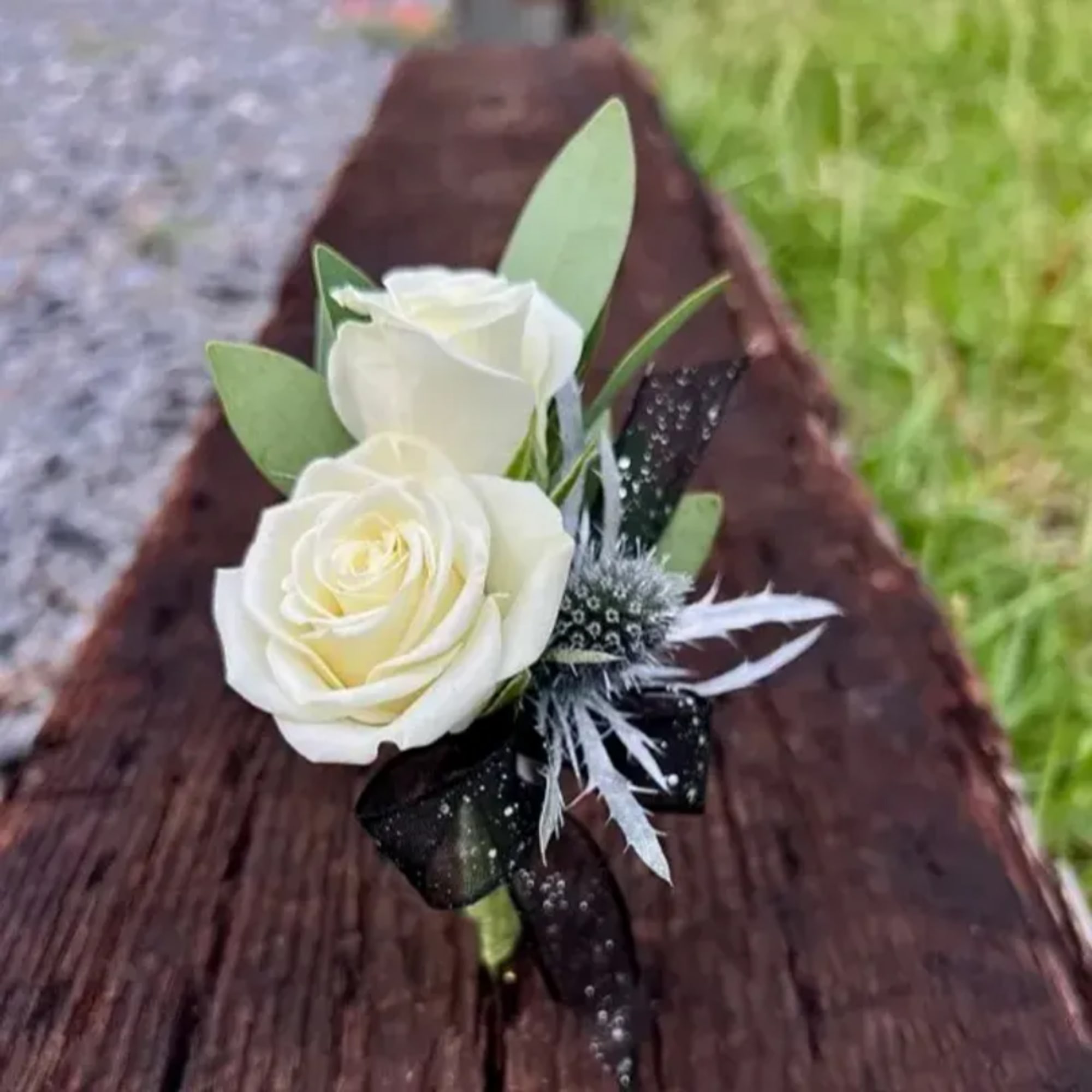 White rose boutonniere with black ribbon and silver accents