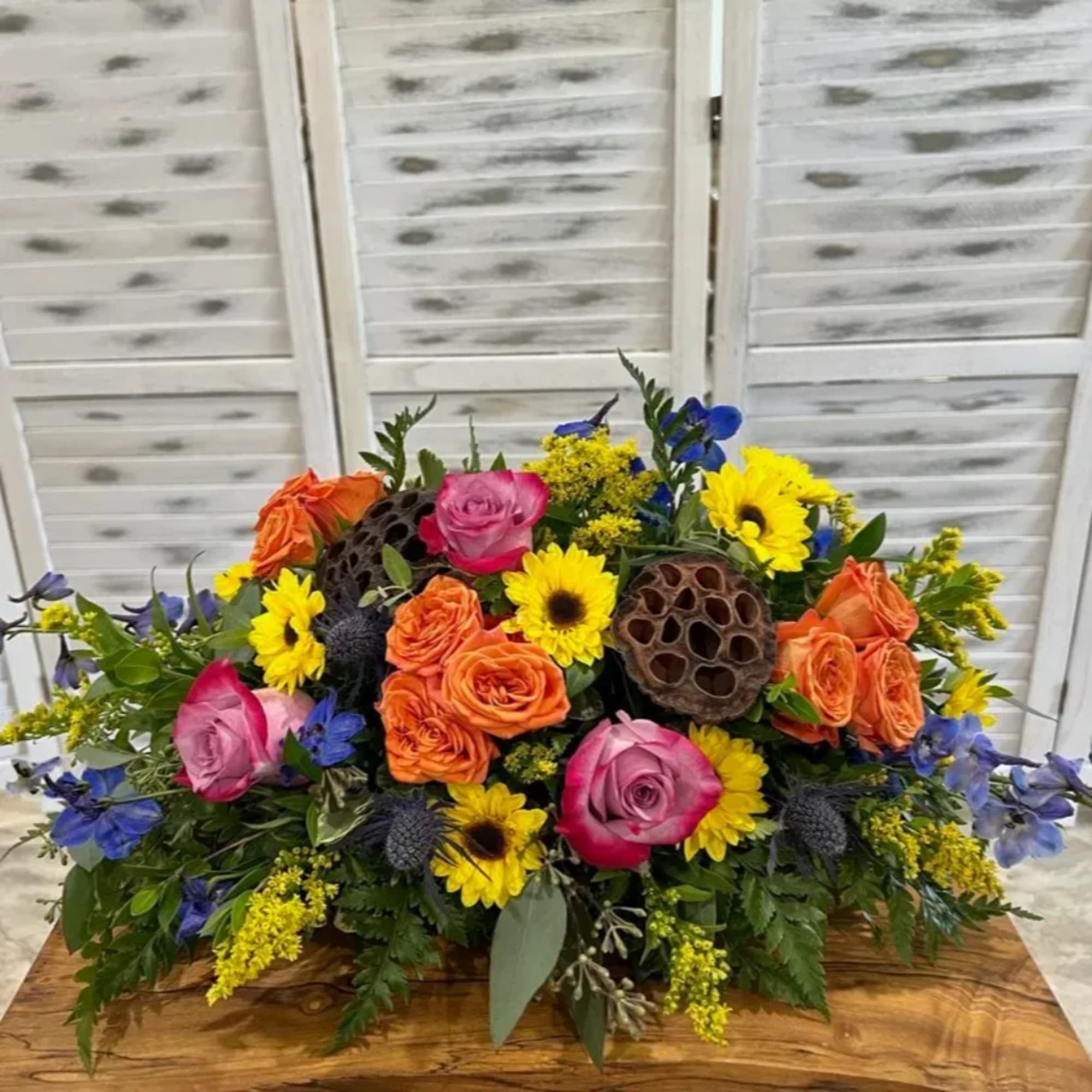 Colorful mixed flower arrangement with roses and sunflowers in a low centerpiece