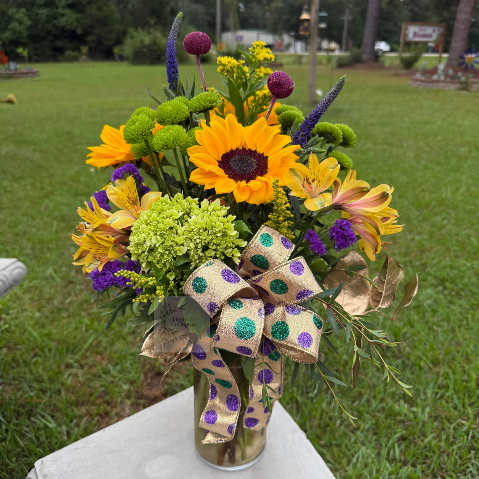 Bright mixed bouquet in a gold vase with a polka-dot ribbon