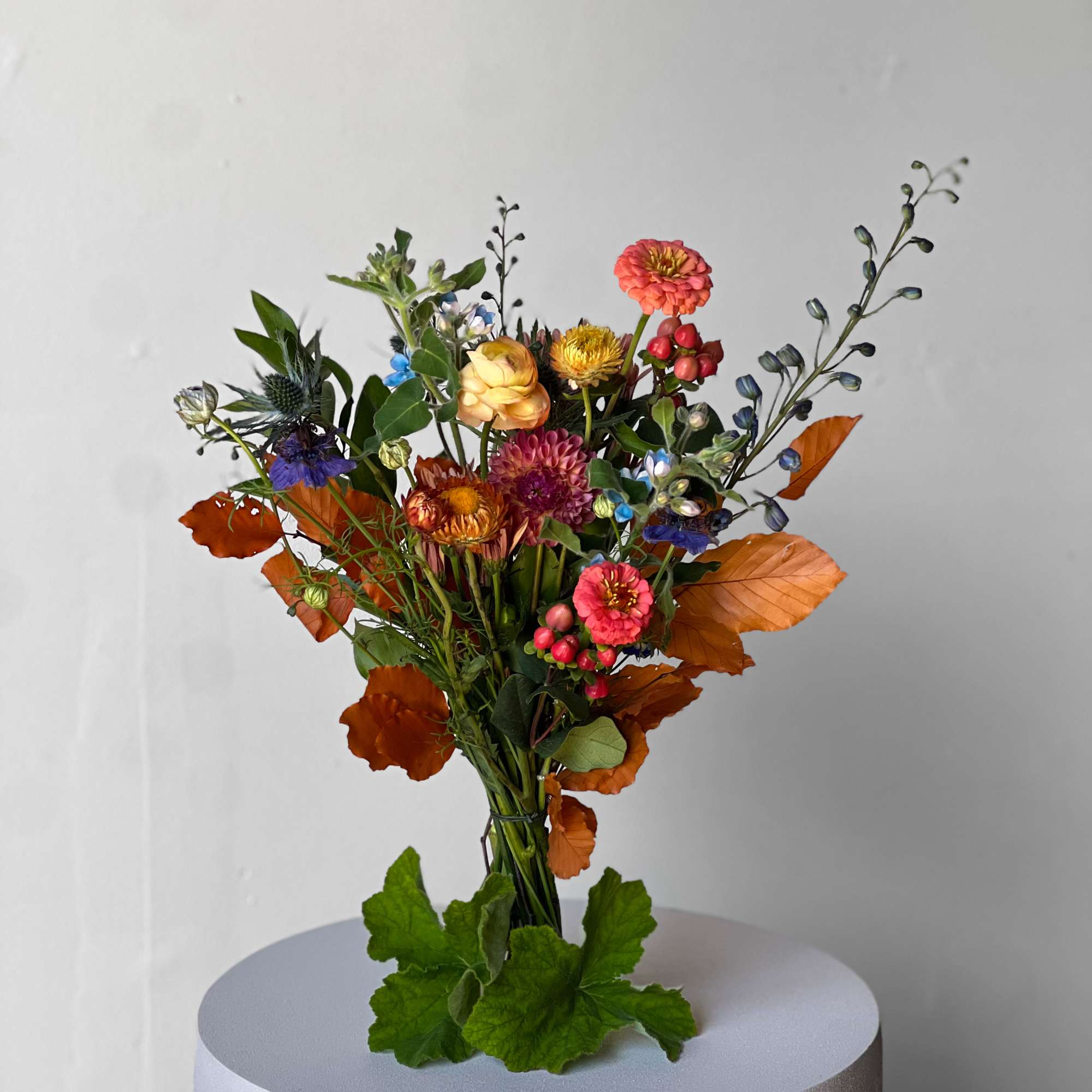 Mixed bouquet with orange, pink, yellow, and blue flowers on a pedestal