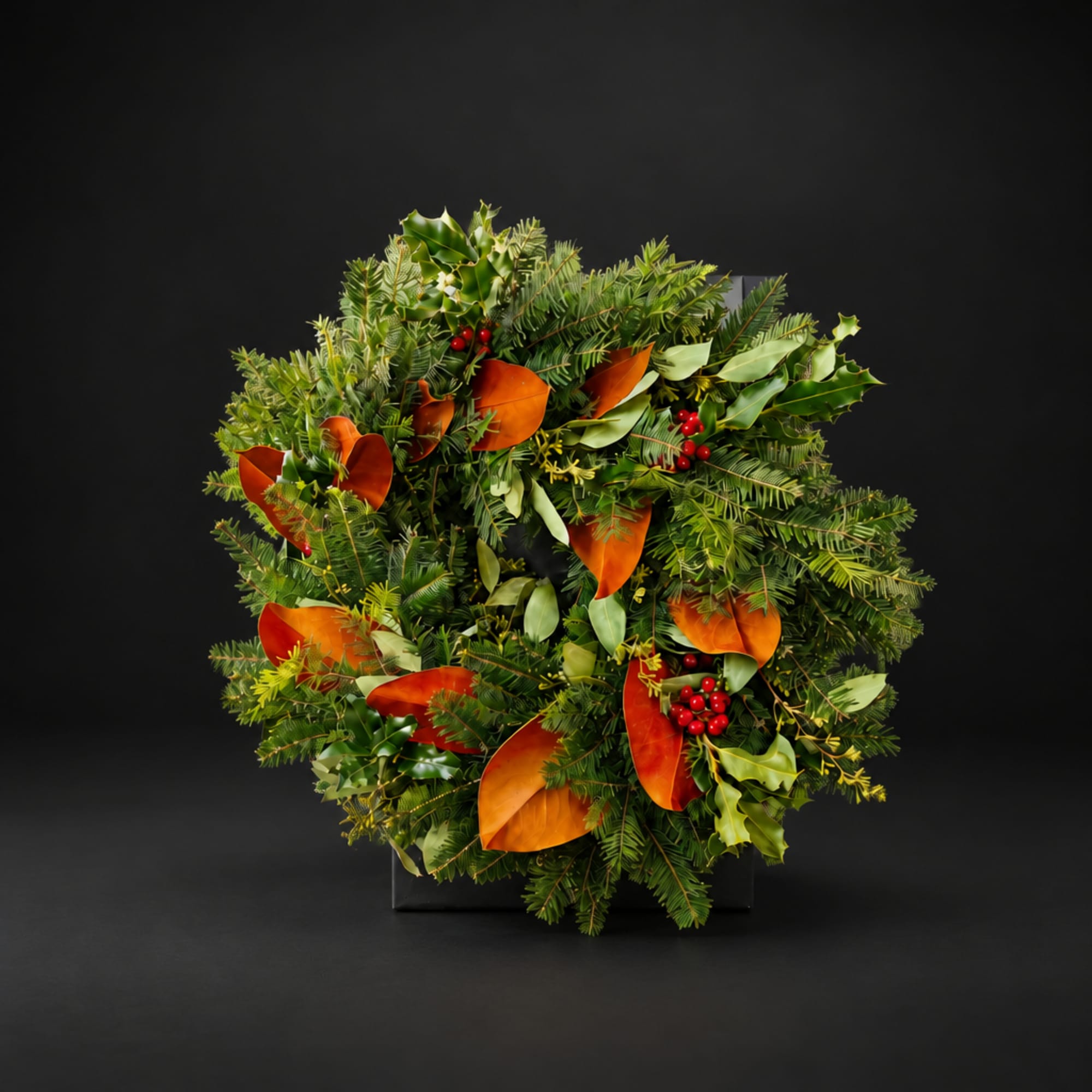 Holiday wreath with evergreen branches, orange leaves, and red berries