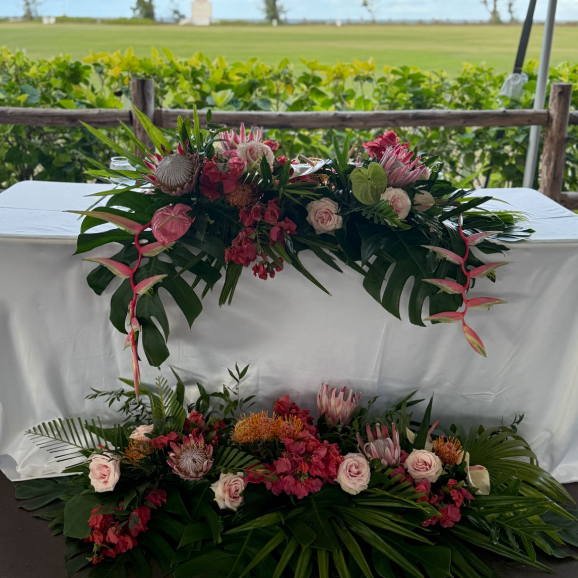 Wedding floral arrangements with pink and white blooms and tropical leaves on a table