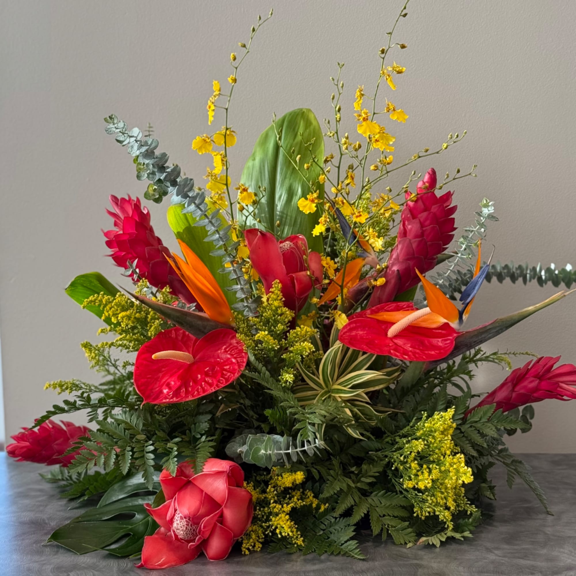 Tropical floral arrangement with red anthuriums, pink ginger, and bird of paradise